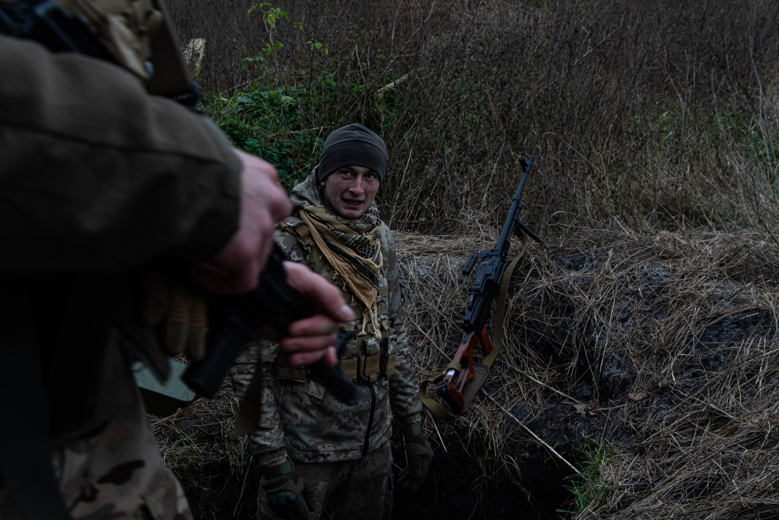 Un soldat ukrainien en poste de surveillance dans une petite tranchée.