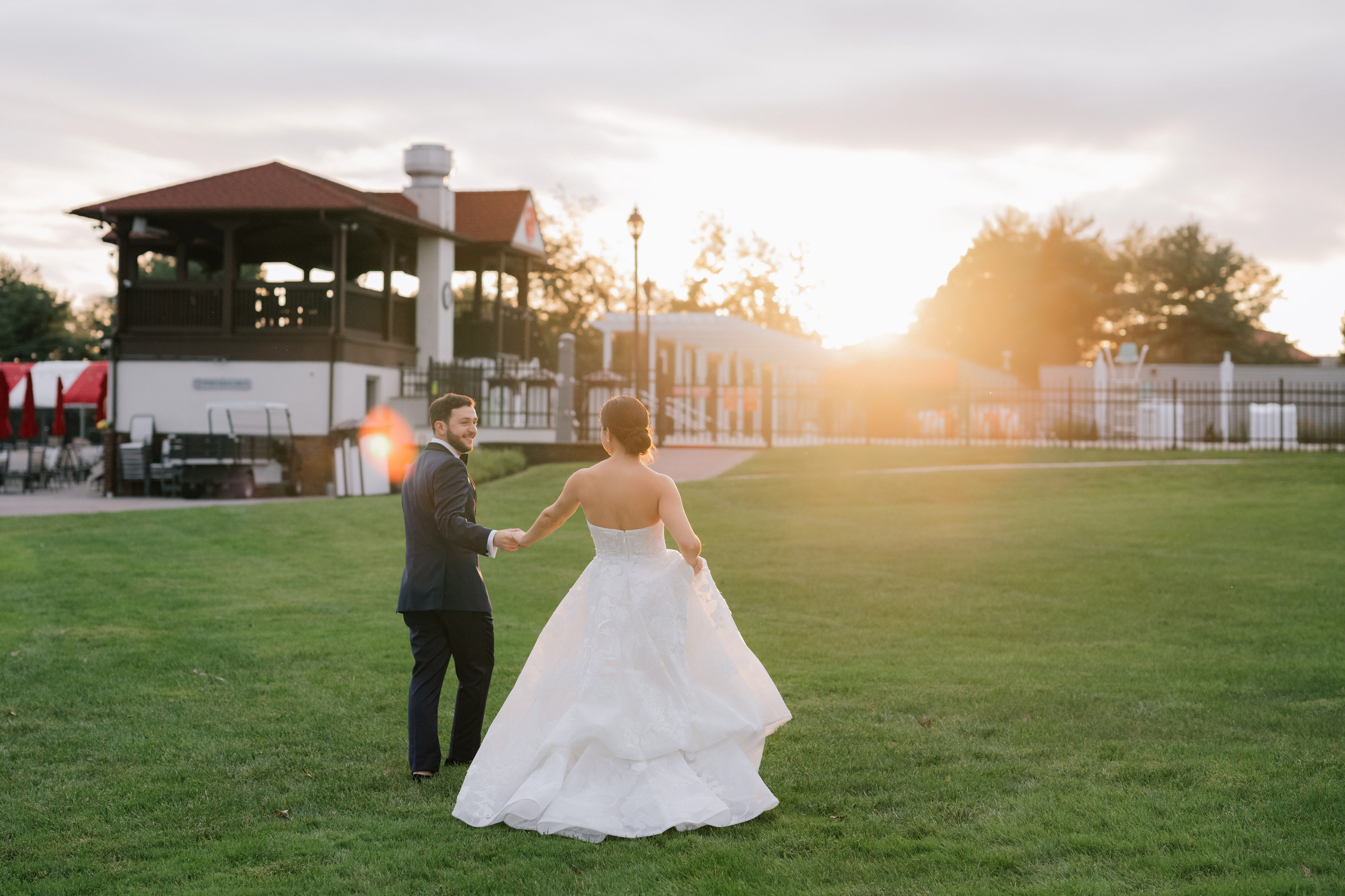 a bride and groom walking in a field