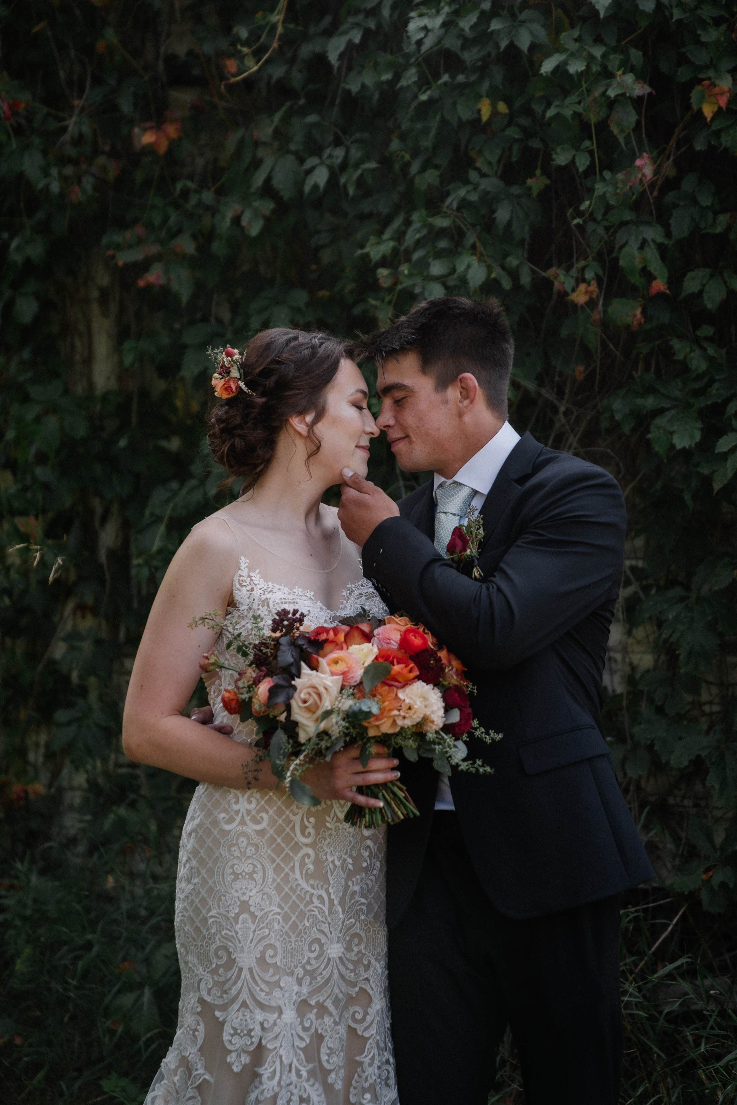 Bride and groom standing together with a bouquet, bride in a wedding dress and groom in a suit.