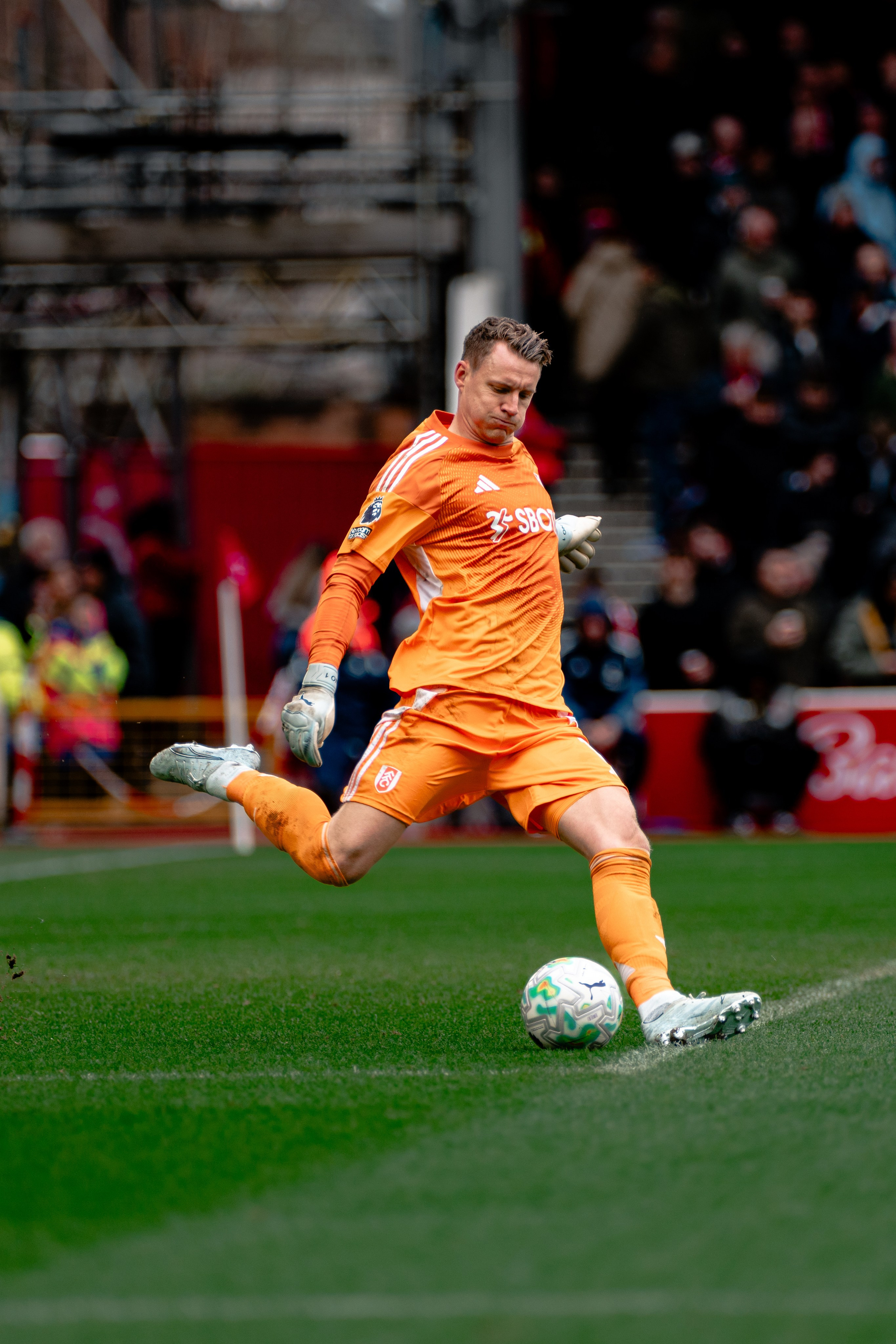 Nottingham Forest goalkeeper in an orange kit controlling the ball during the Premier League match against Fulham.