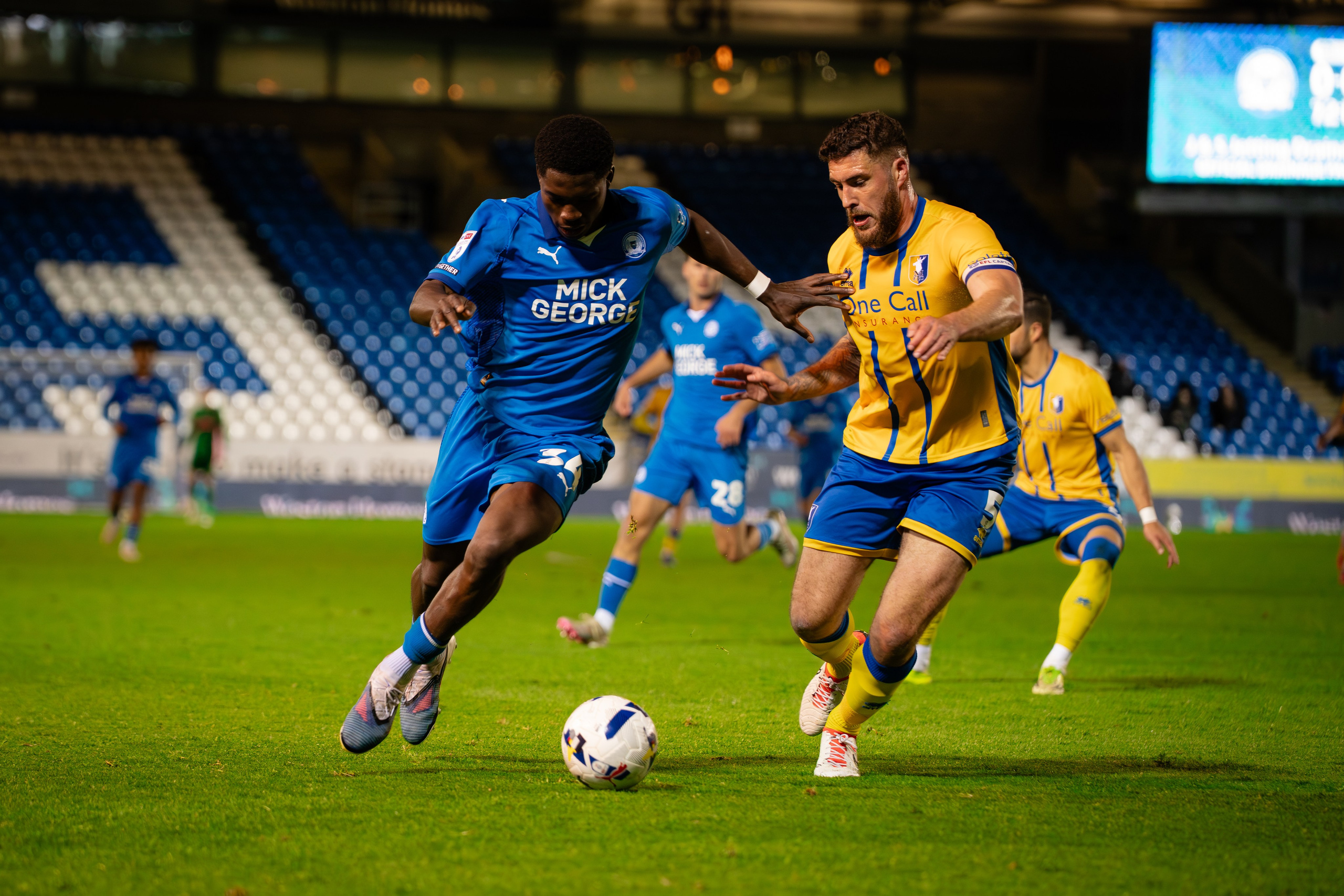 Peterborough United player dribbling past a Mansfield Town defender during their League One match on 28 April 2026.