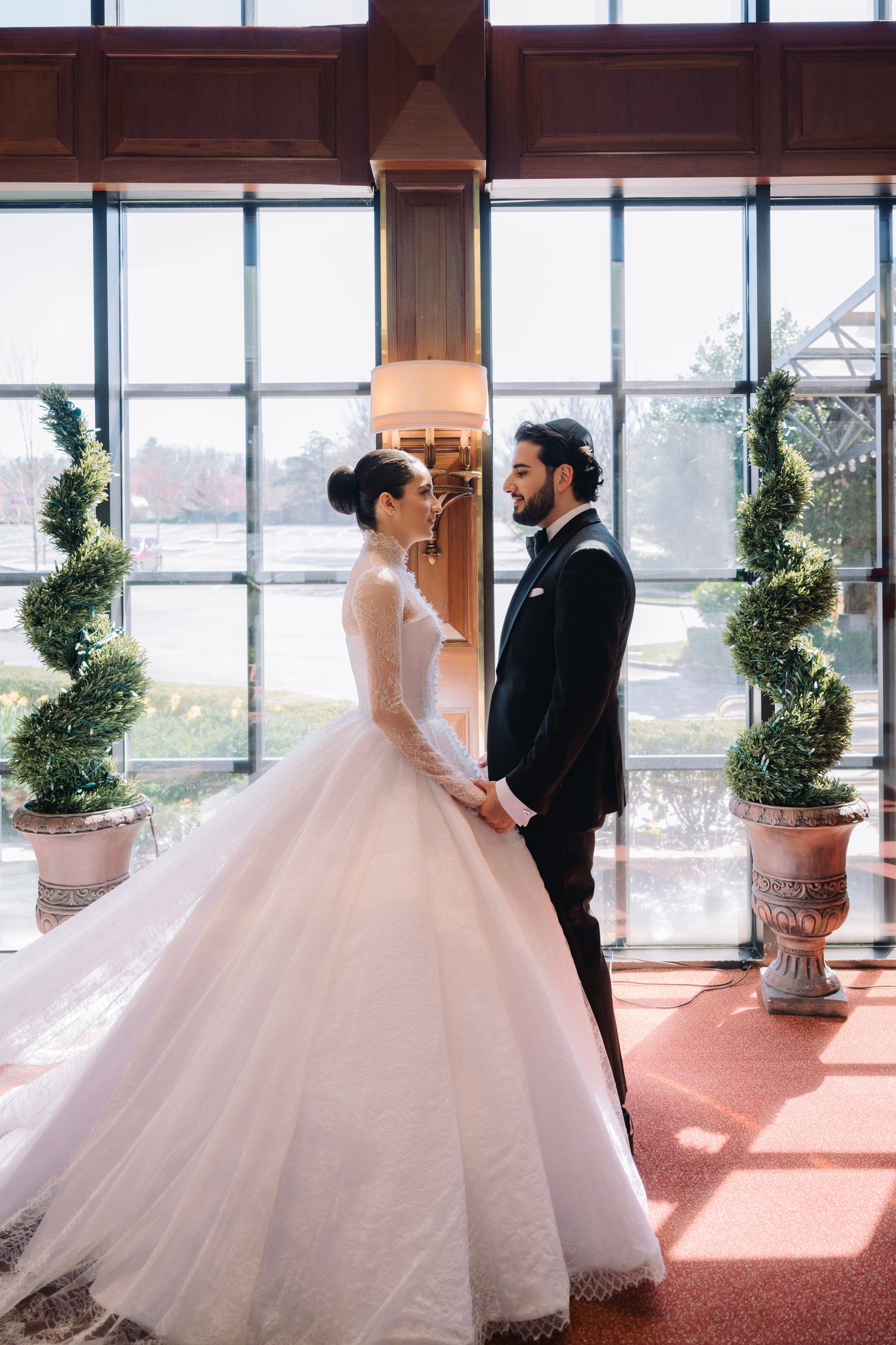 a bride and groom standing in front of a window