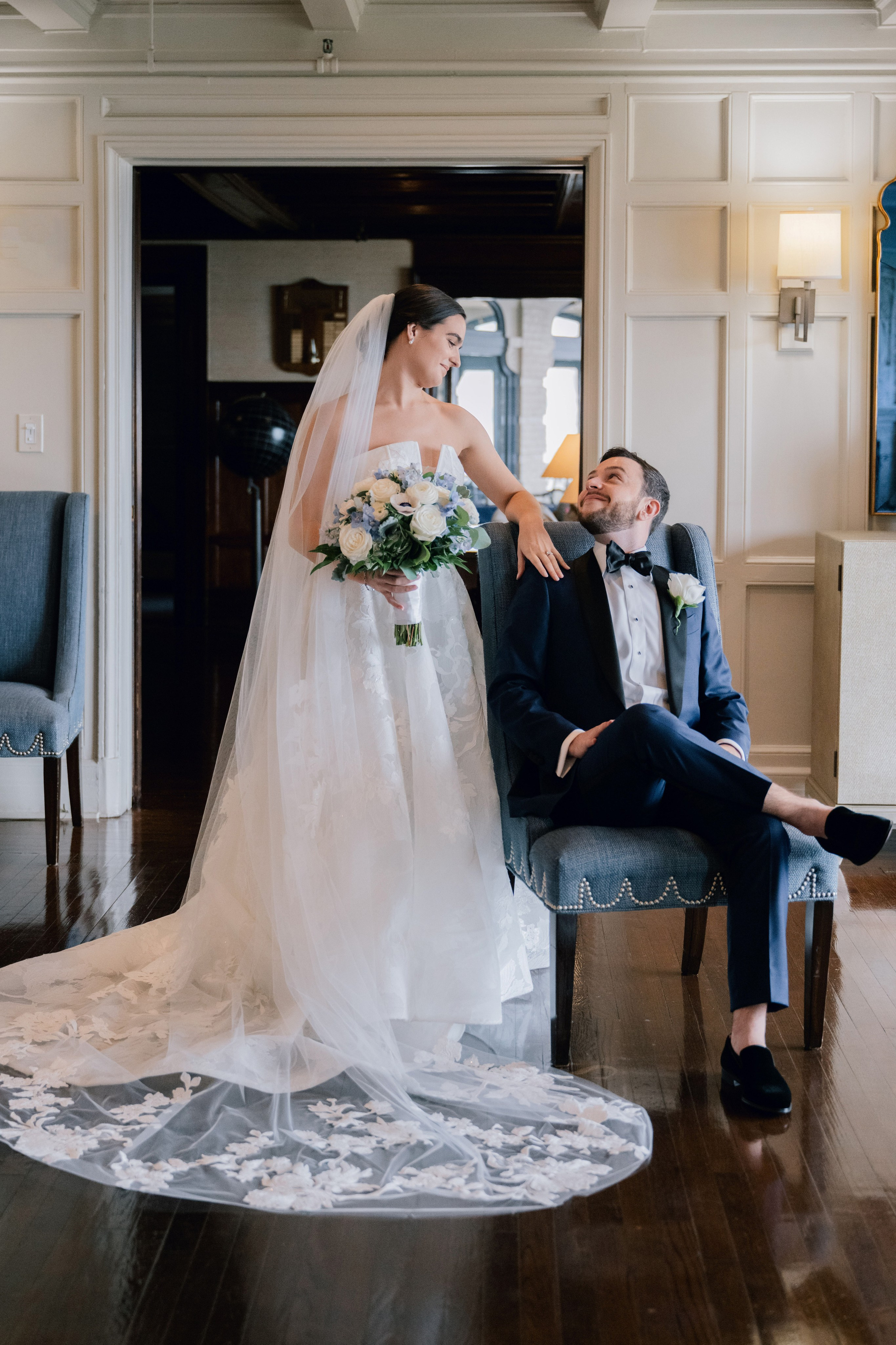 a bride and groom sitting on a chair in a room