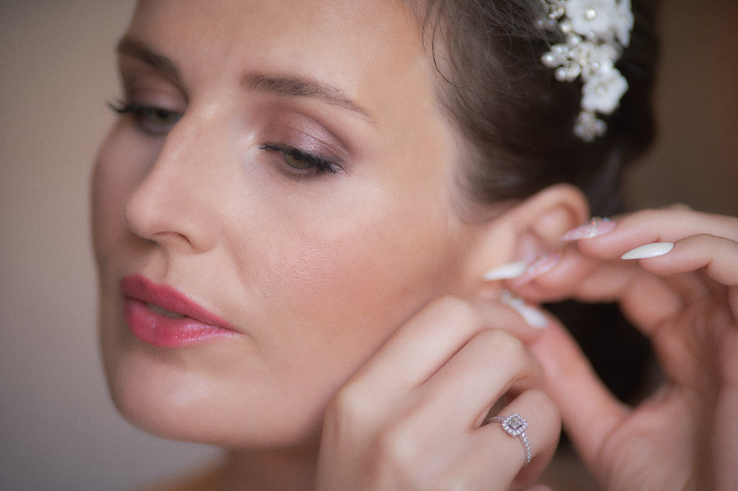 A close up view of a brunette bride as she puts in her earrings that she will wear for her Prague wedding.
