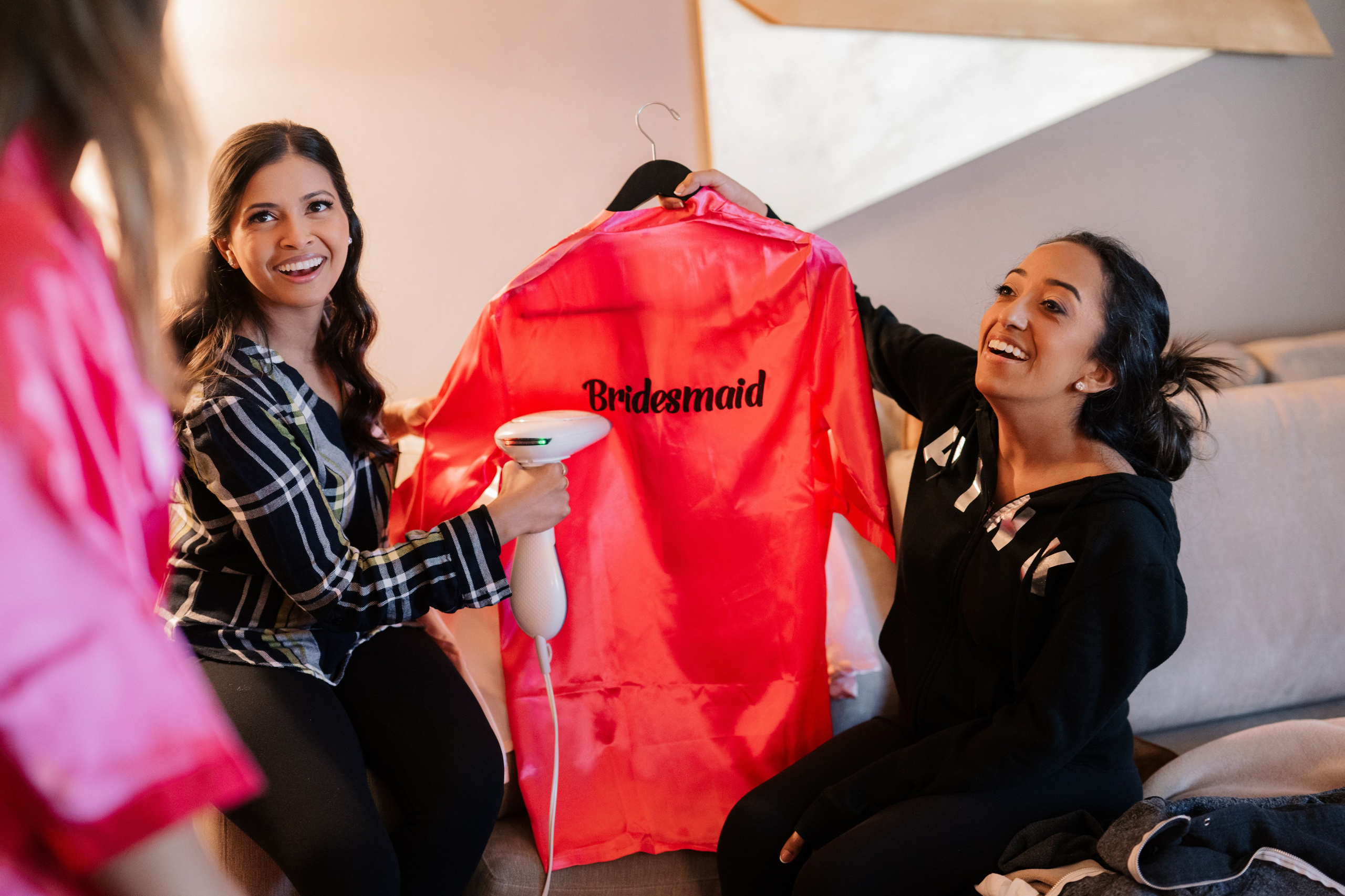 two women sitting on a couch holding a red shirt