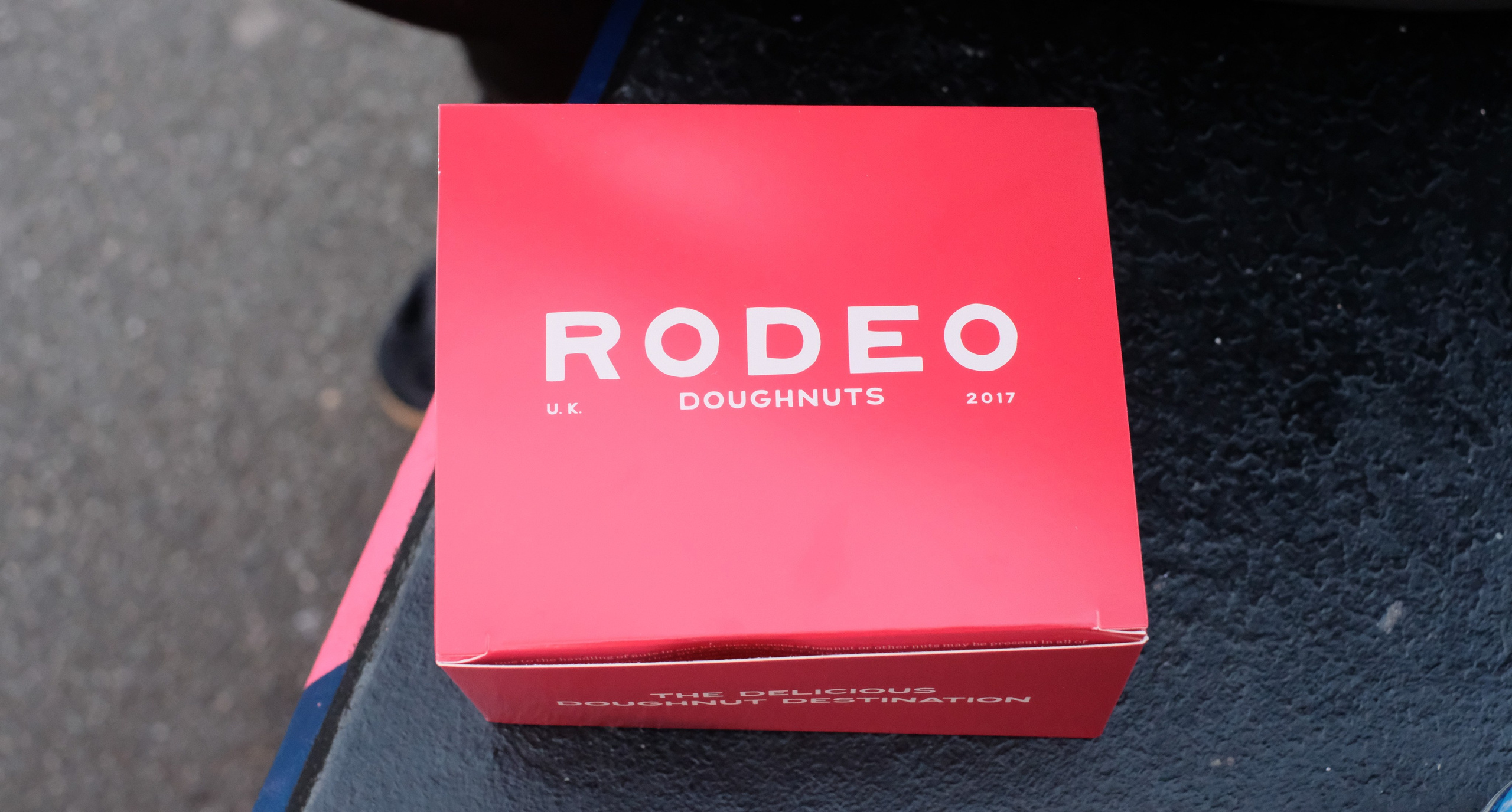 A bright pink Rodeo Doughnuts box on a dark tabletop.