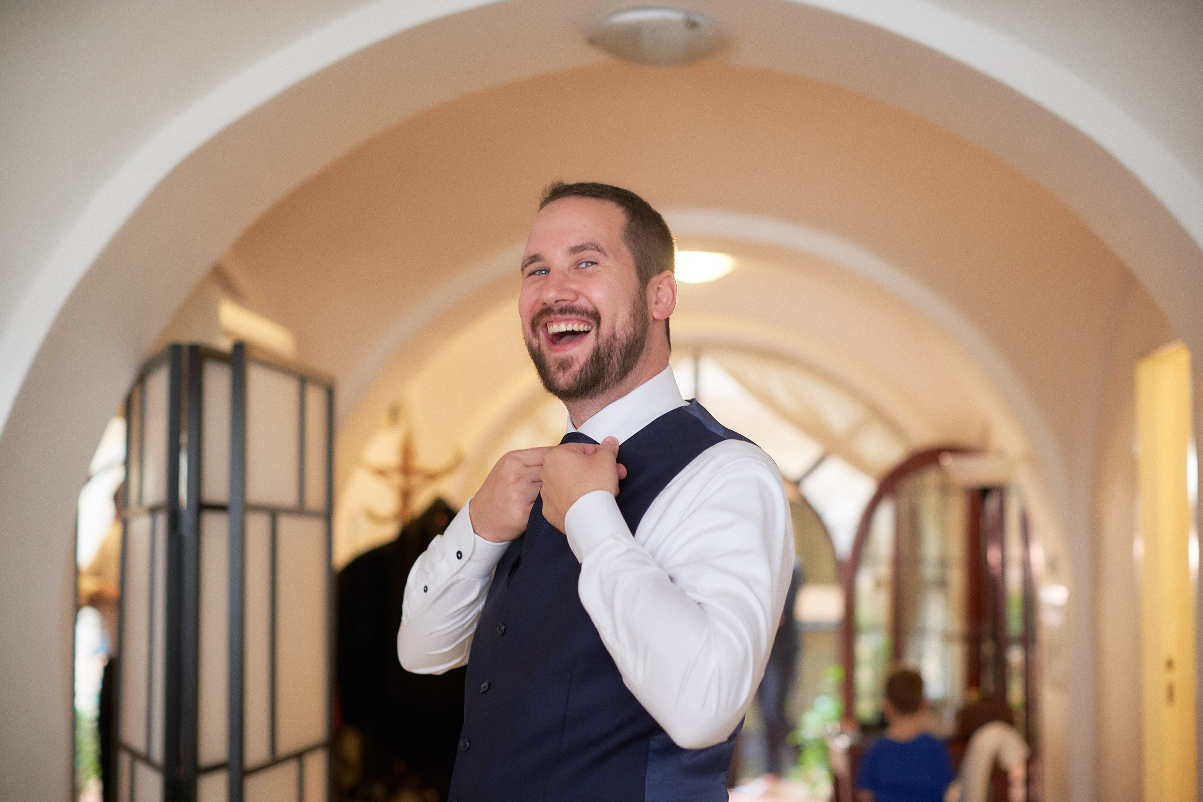 Joyful restaurateur groom smiling during wedding day preparations.