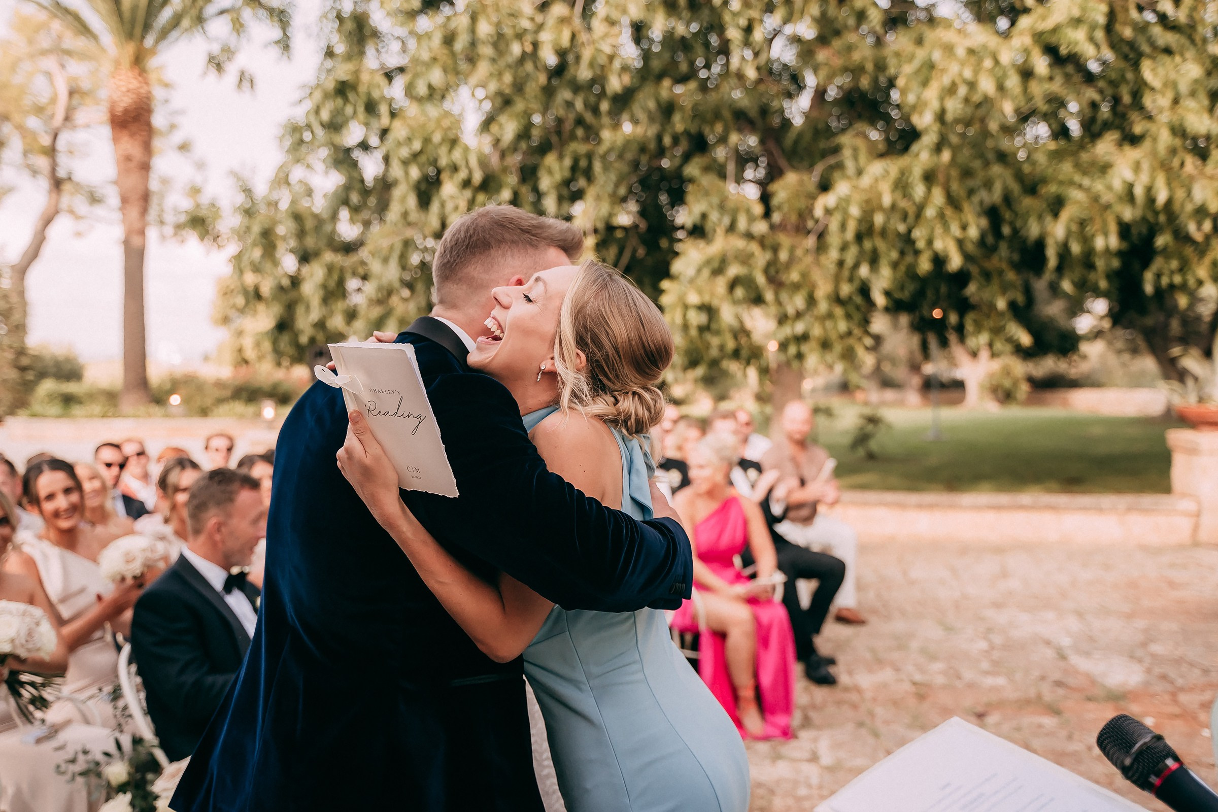 The groom and a close friend sharing a heartfelt embrace, radiating joy amidst the lush garden setting.