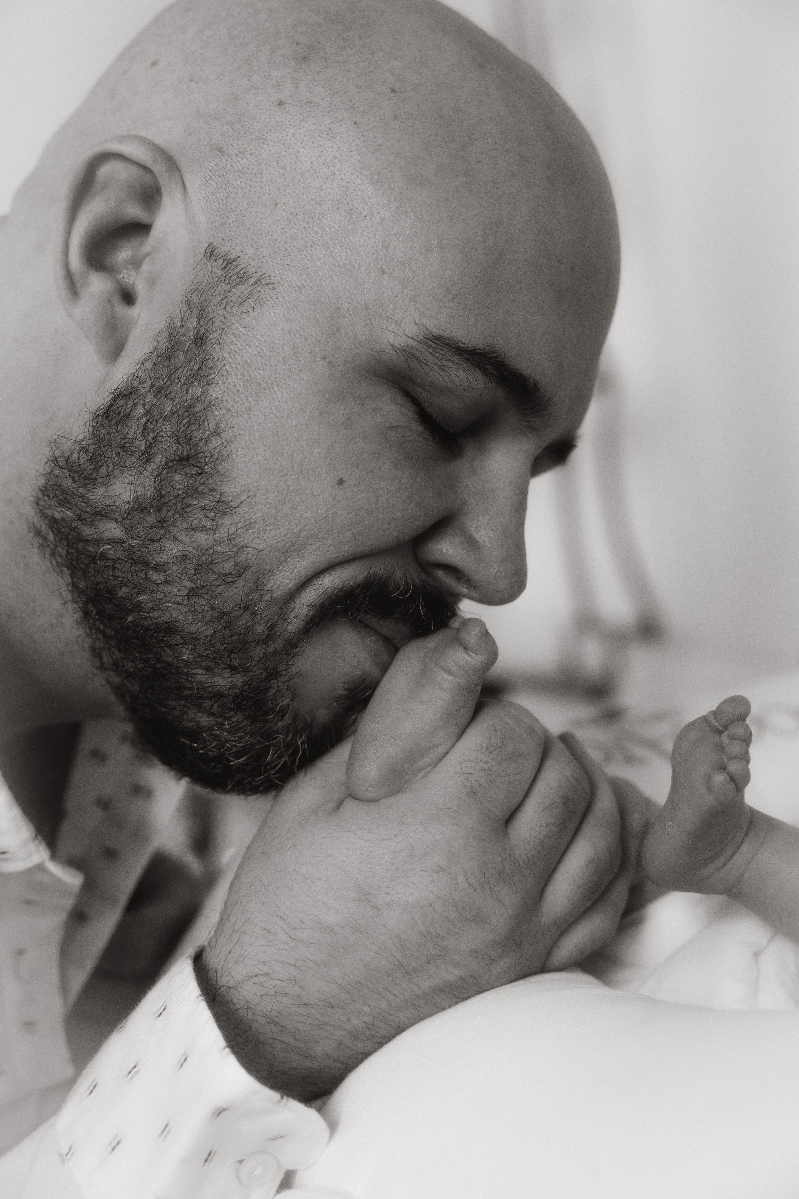 Father gently kissing his newborn baby’s tiny foot, intimate family detail