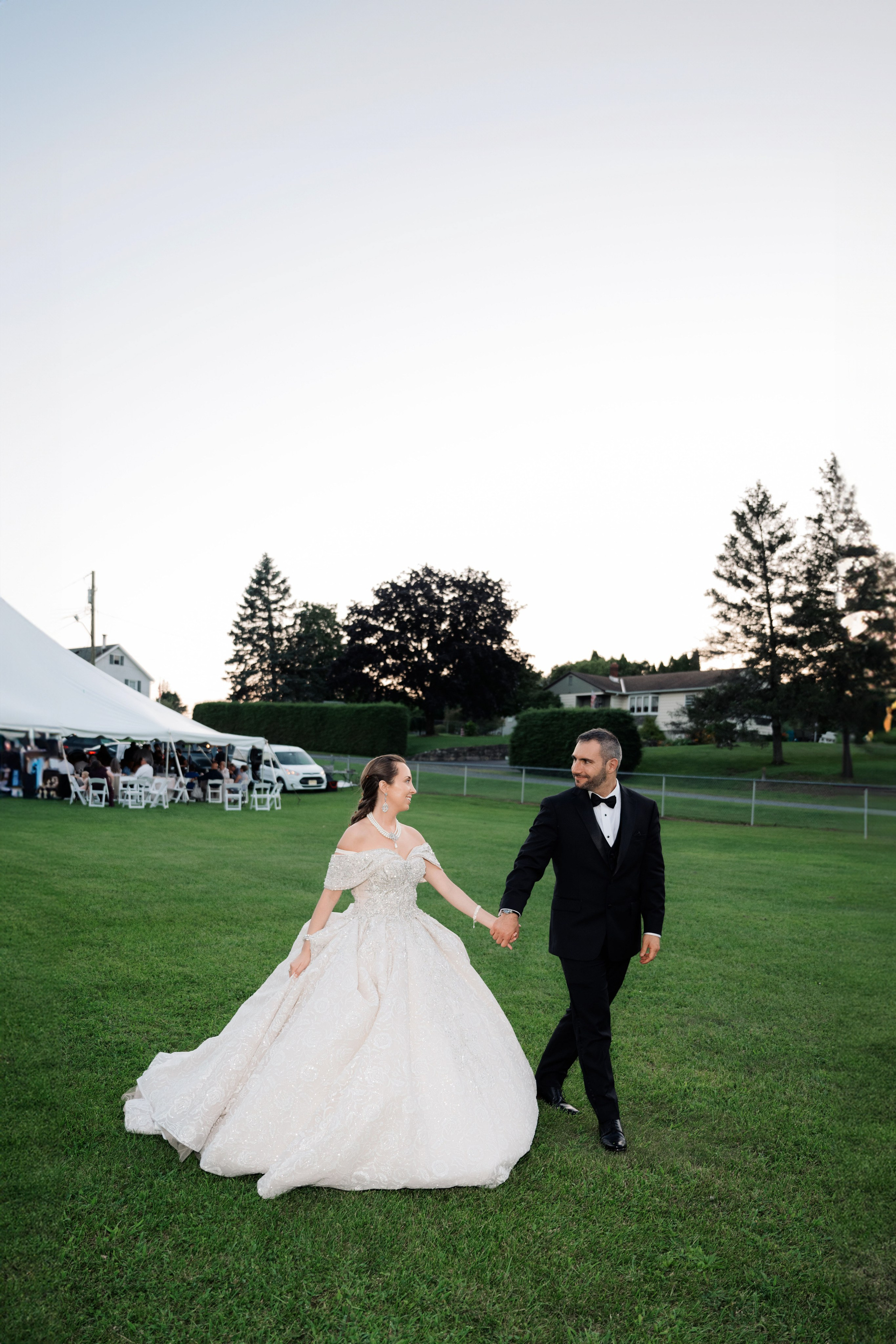 a bride and groom walking through the grass