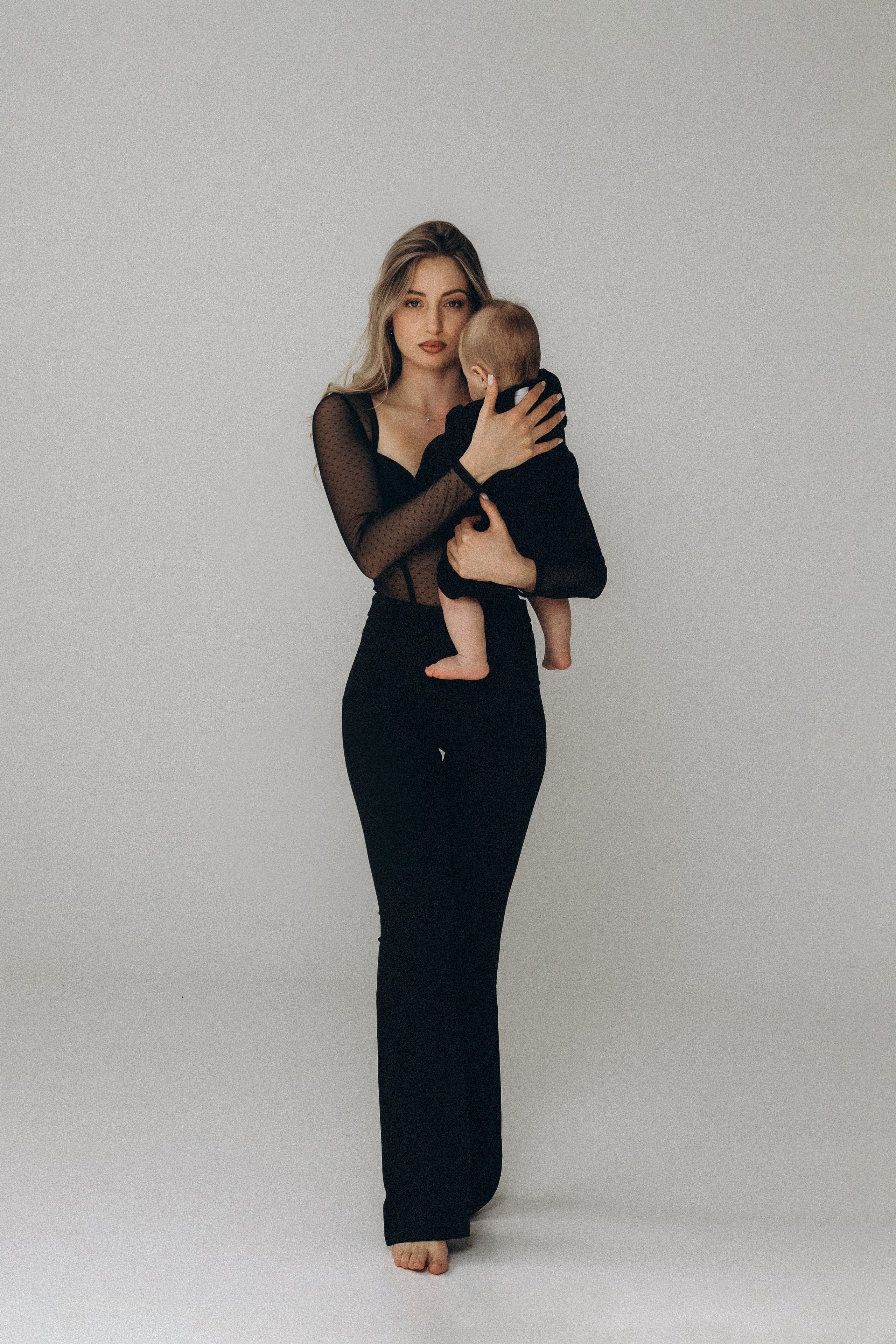 Madre con il suo neonato durante una sessione fotografica di famiglia a San Marino. La luce morbida e il contatto ravvicinato raccontano tenerezza, sicurezza e il legame profondo dei primi mesi insieme.