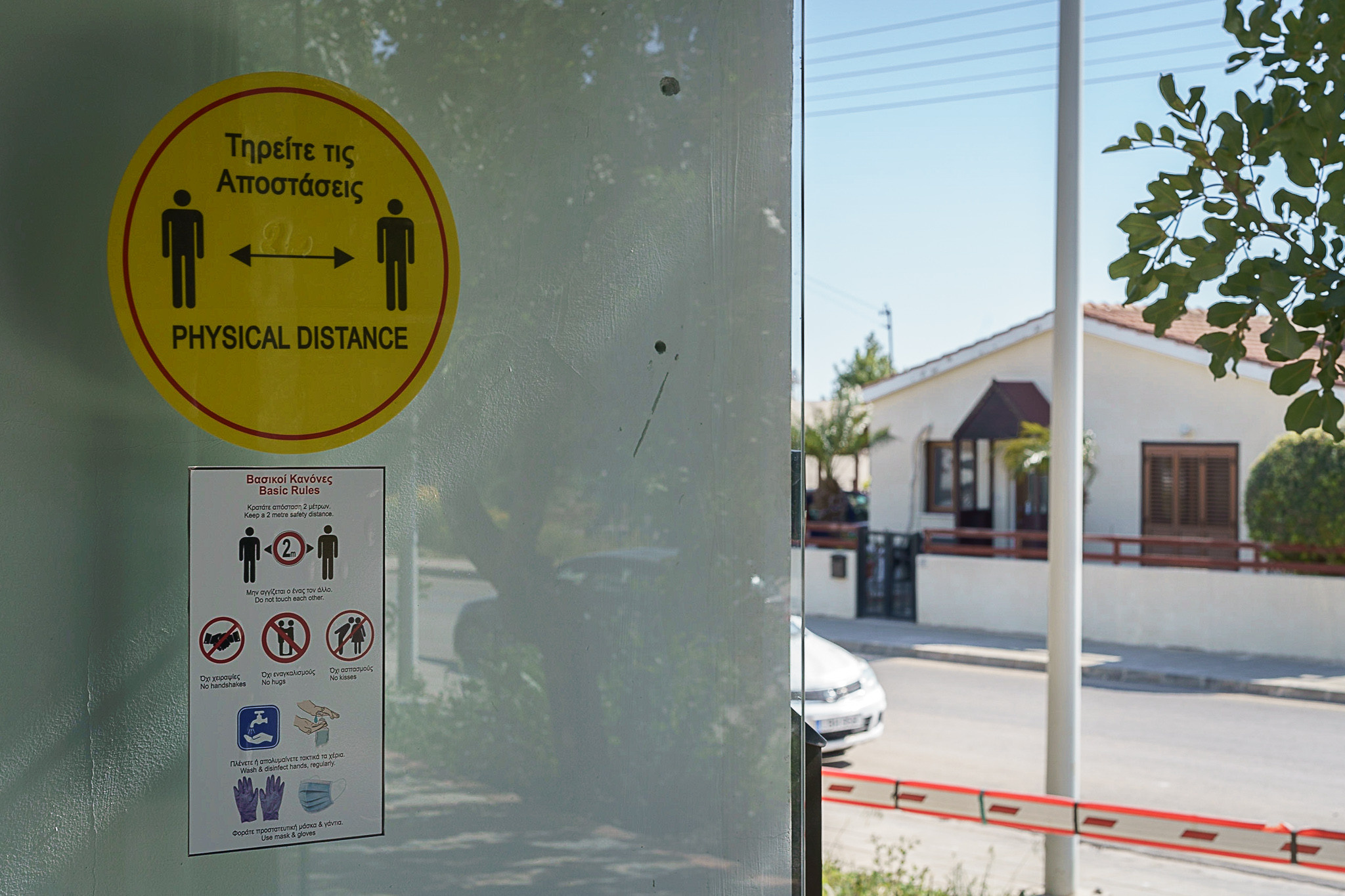 Надпись на английском и греческом: соблюдайте дистанцию 2 метра.