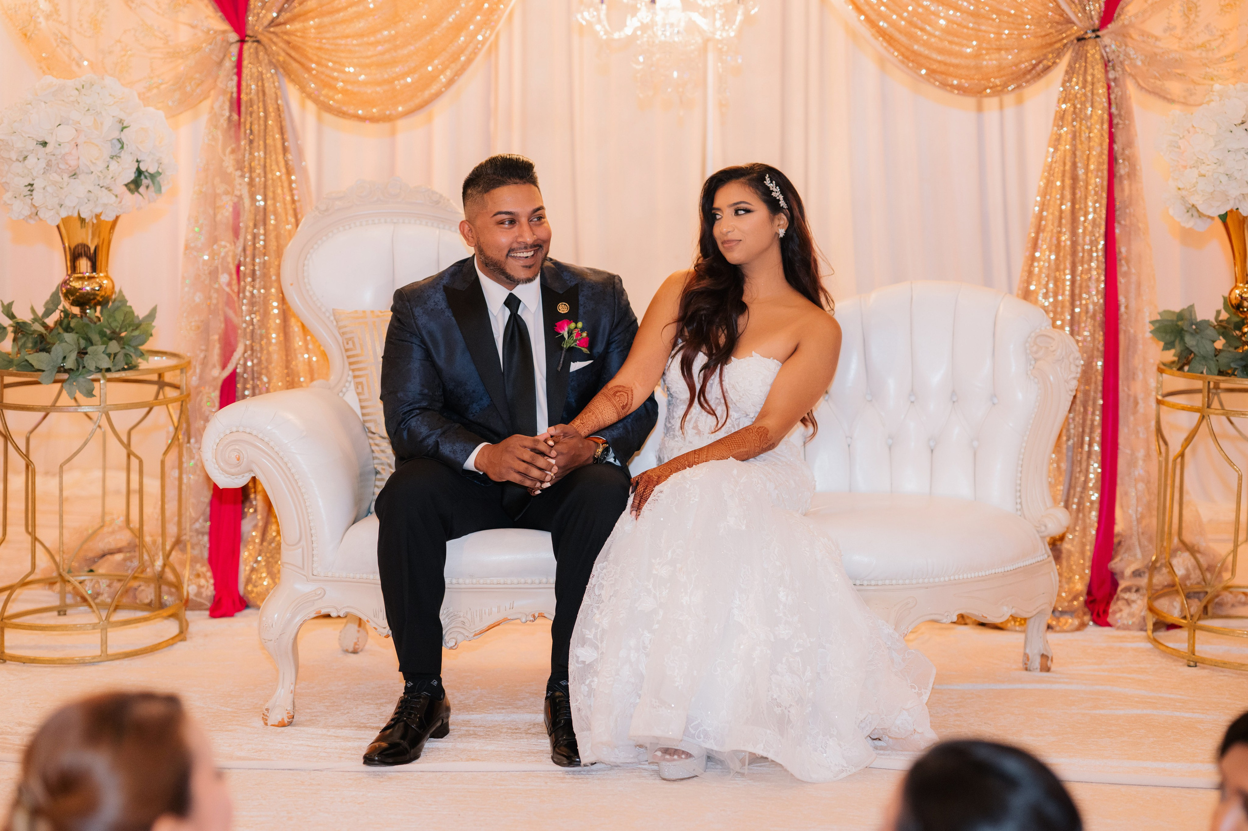 a bride and groom sitting on a white chair