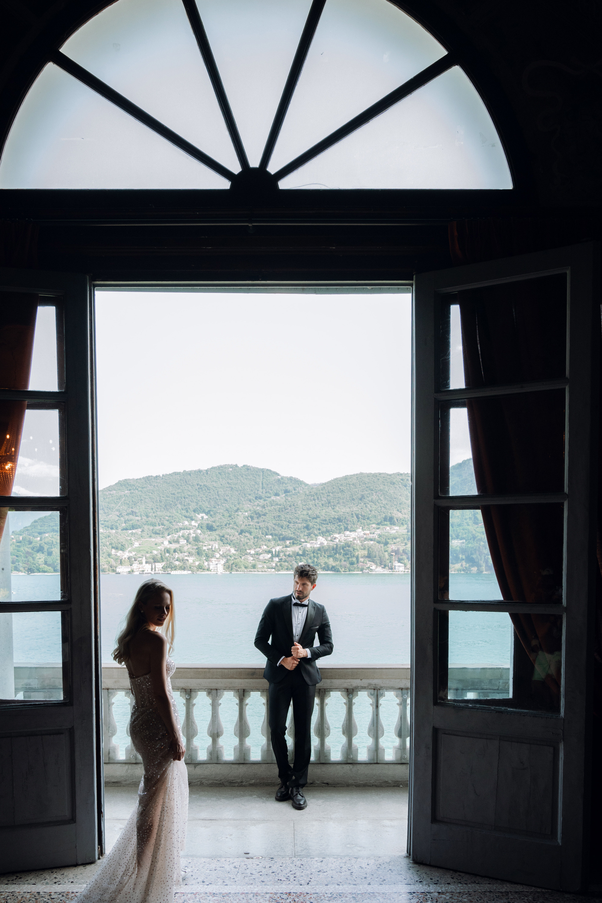 a bride and groom standing in front of a window