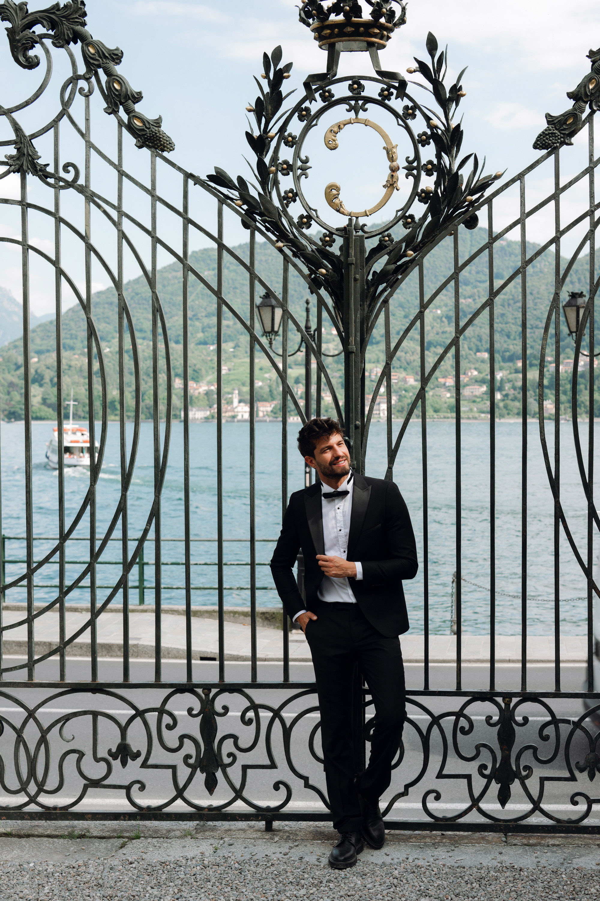 a man in a tuxed suit standing in front of a gate