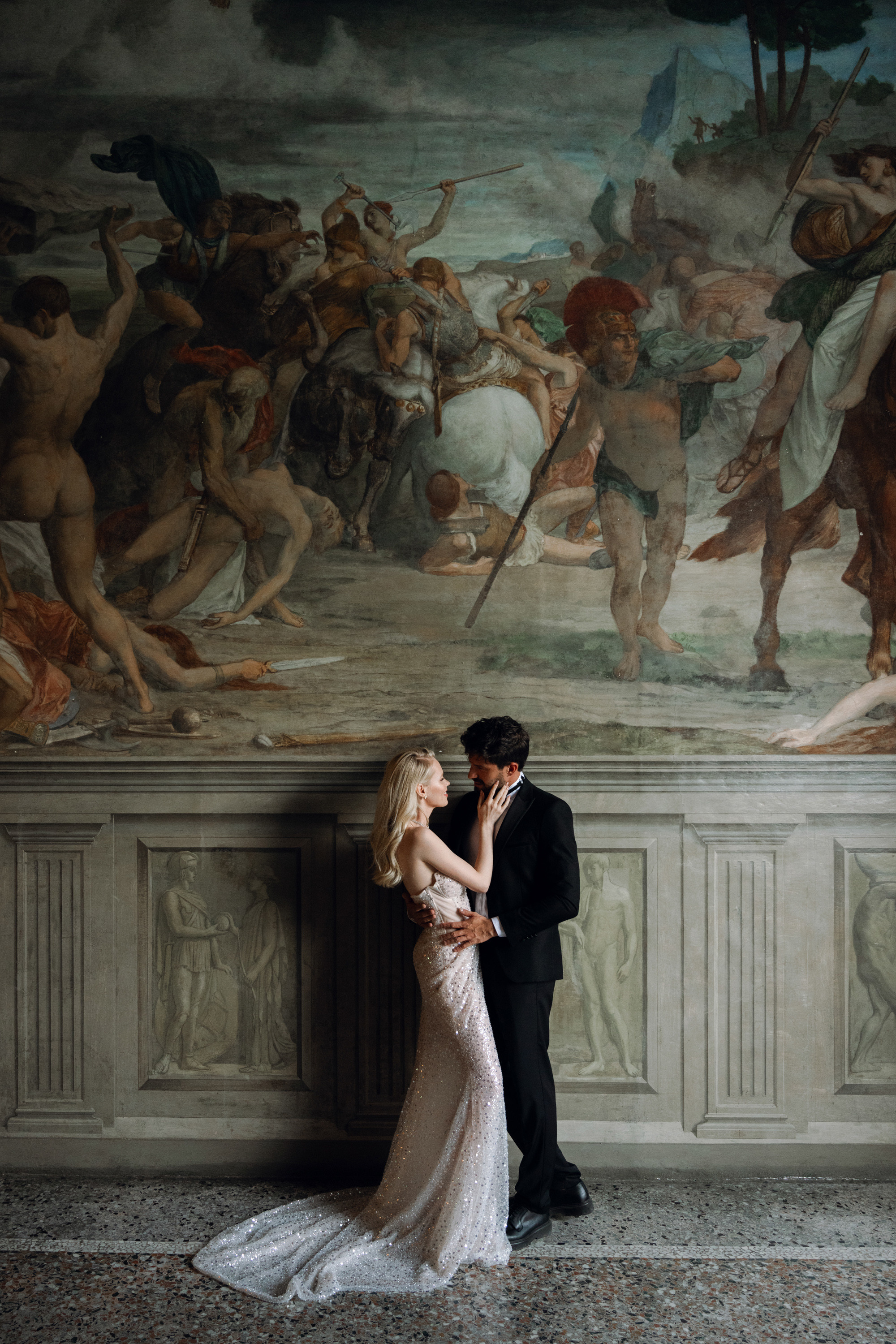 a bride and groom kissing in front of a painting