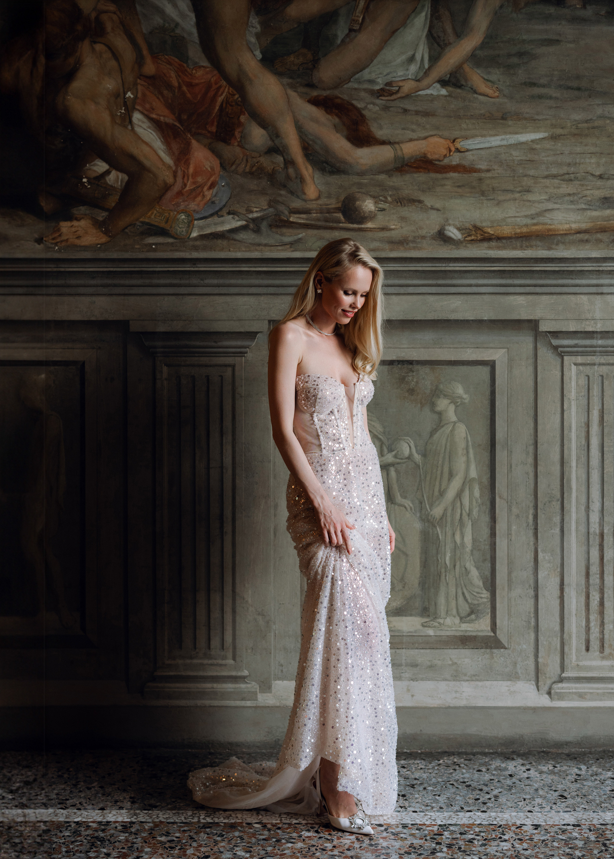 a woman in a wedding dress standing in front of a painting