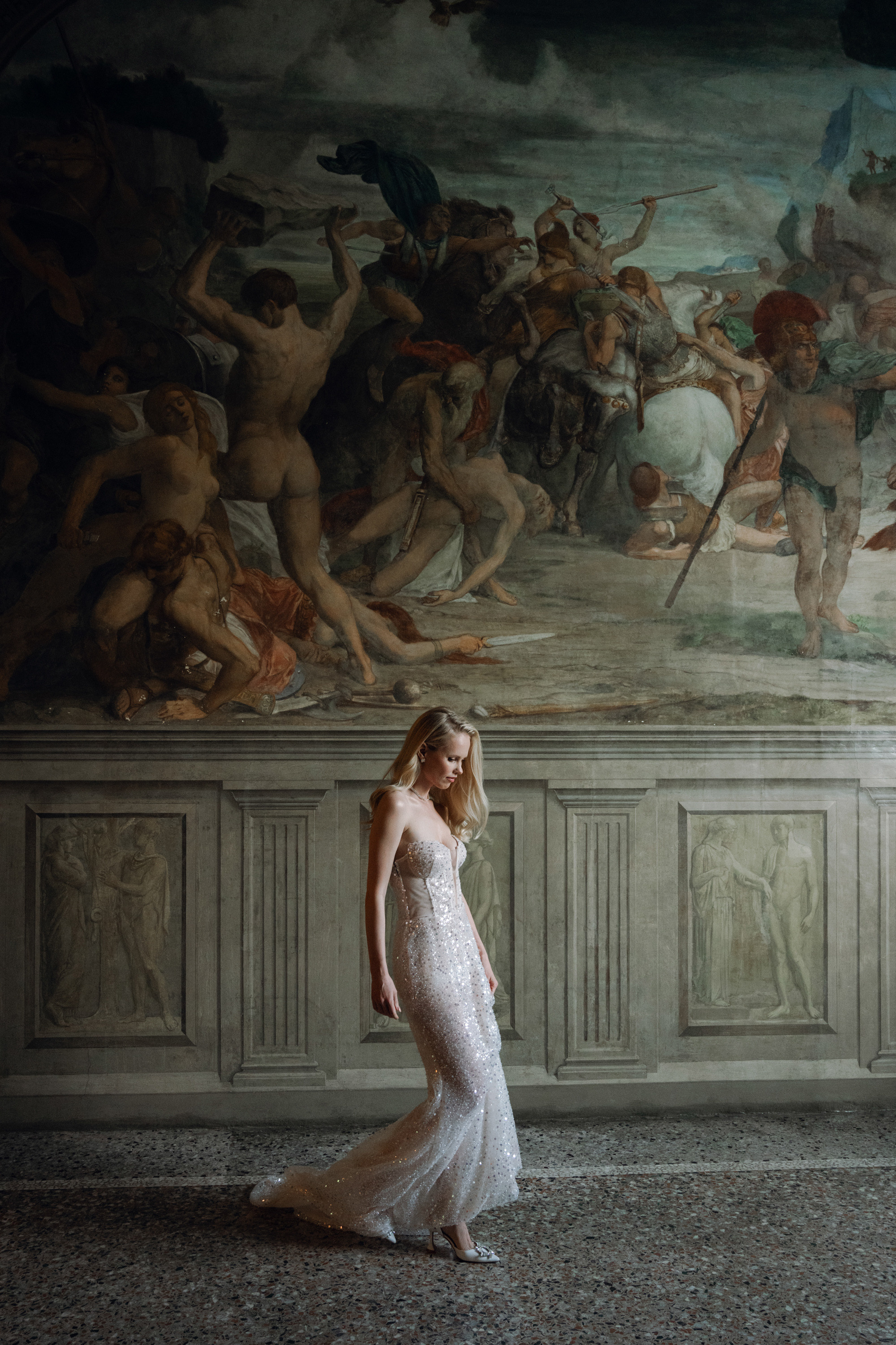 a woman in a wedding dress standing in front of a painting