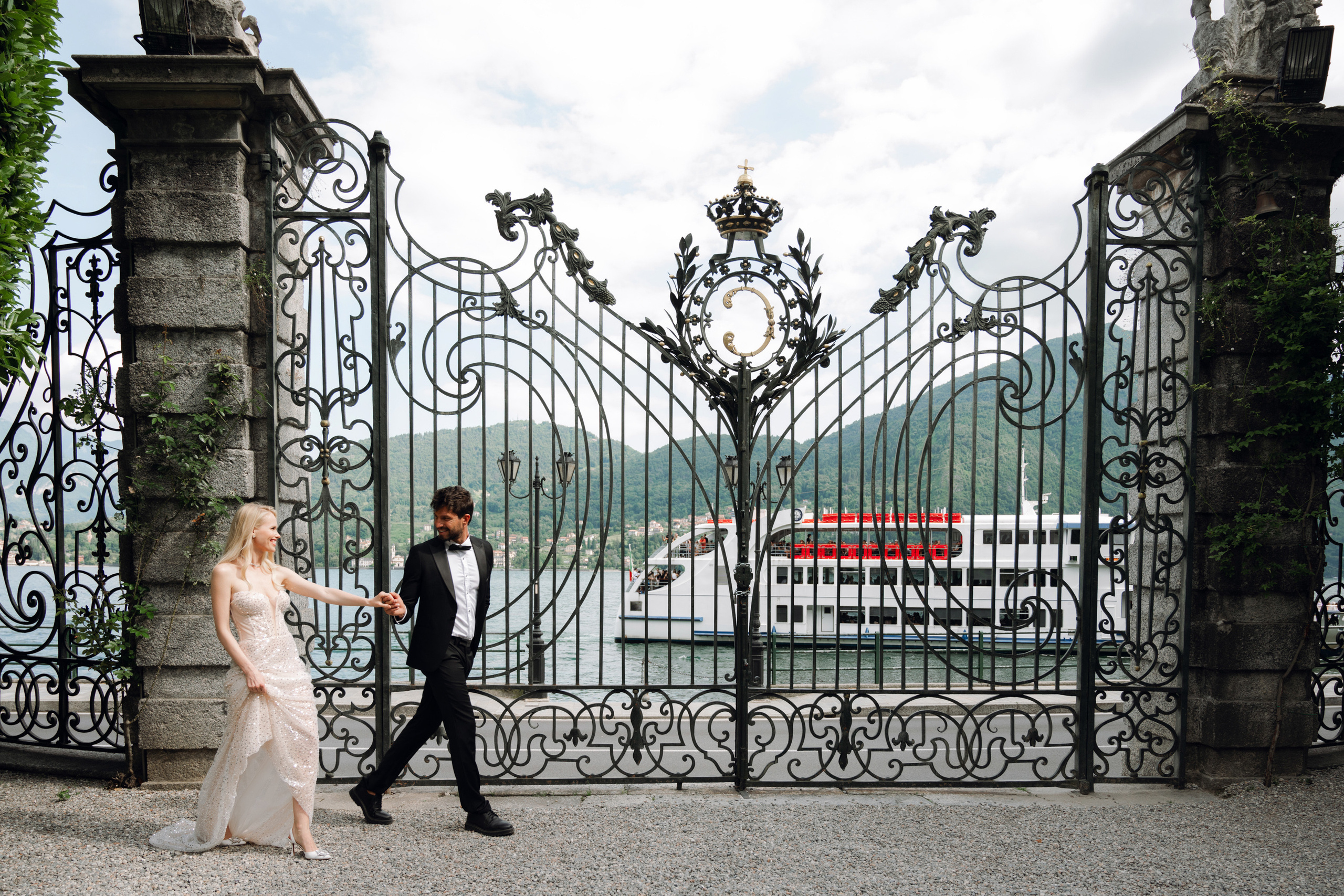 a bride and groom walking in front of a gate