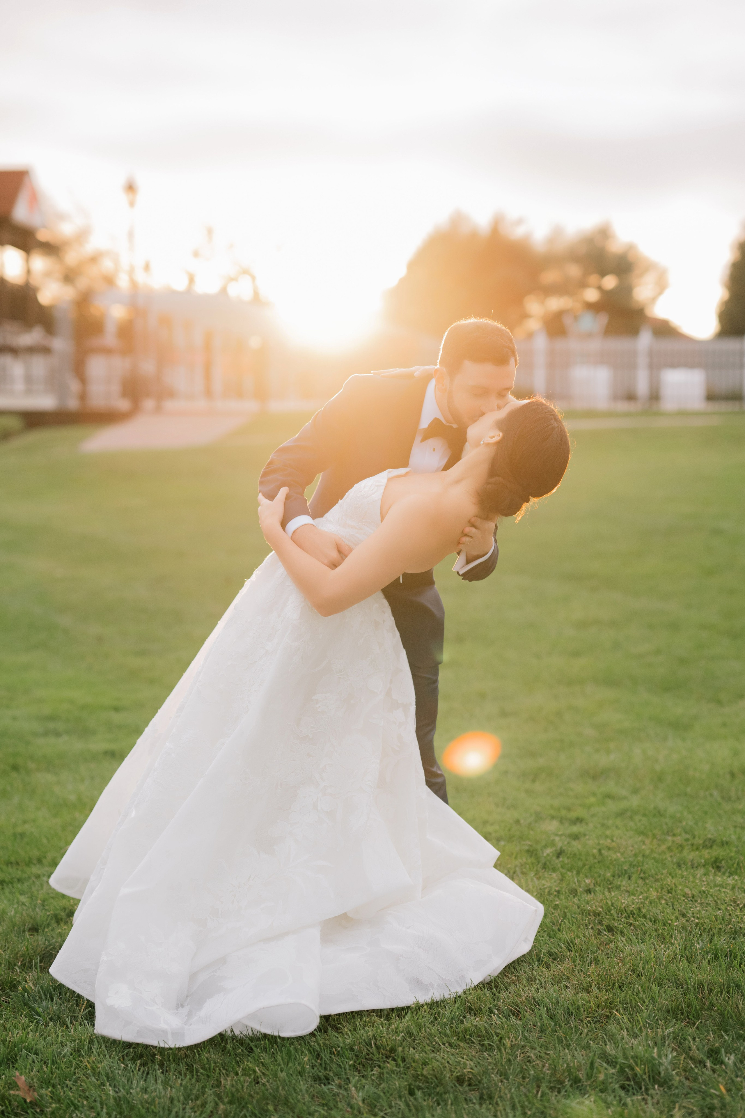 a bride and groom kissing in the grass