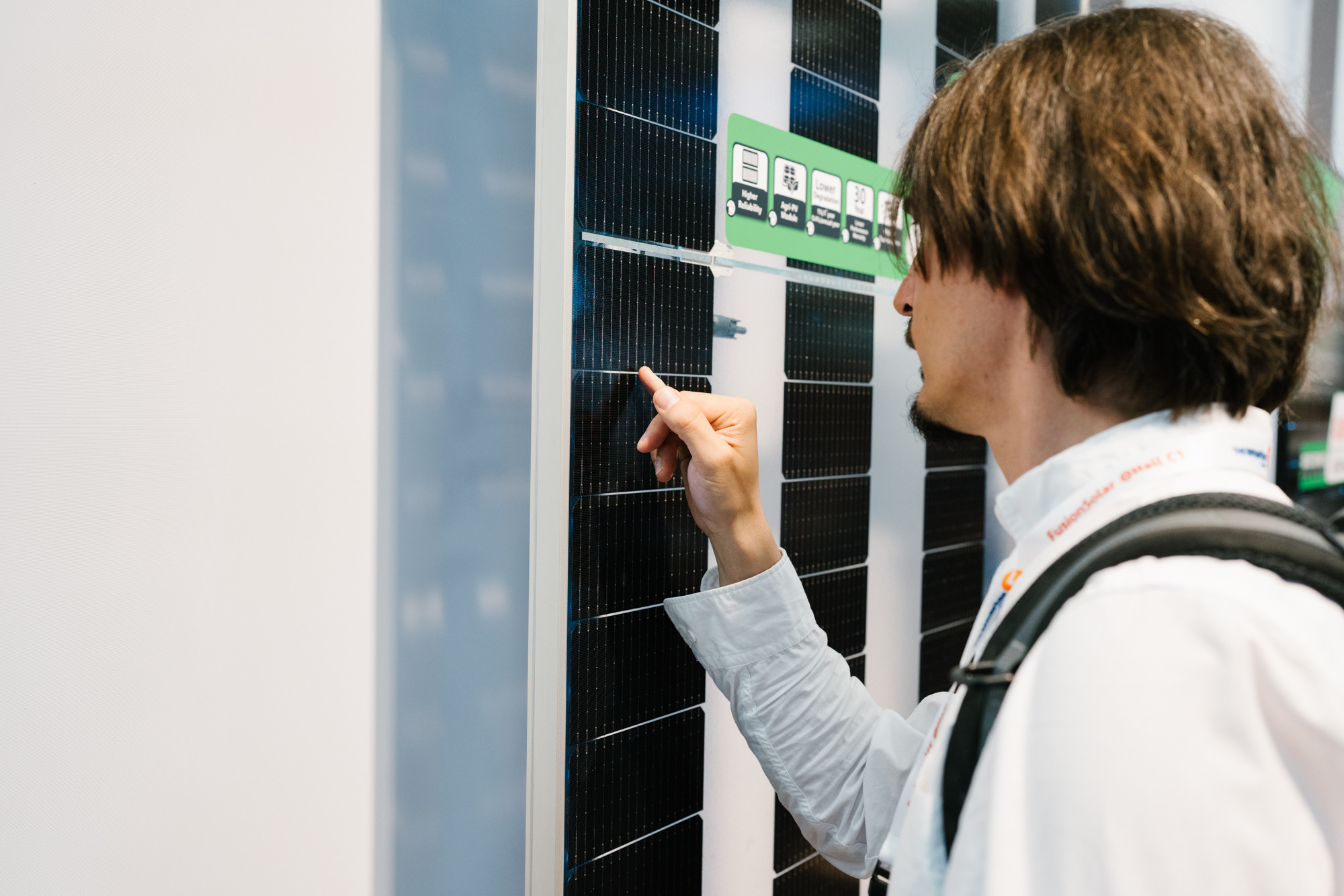 Besucher betrachtet ein Solarmodul am Messestand