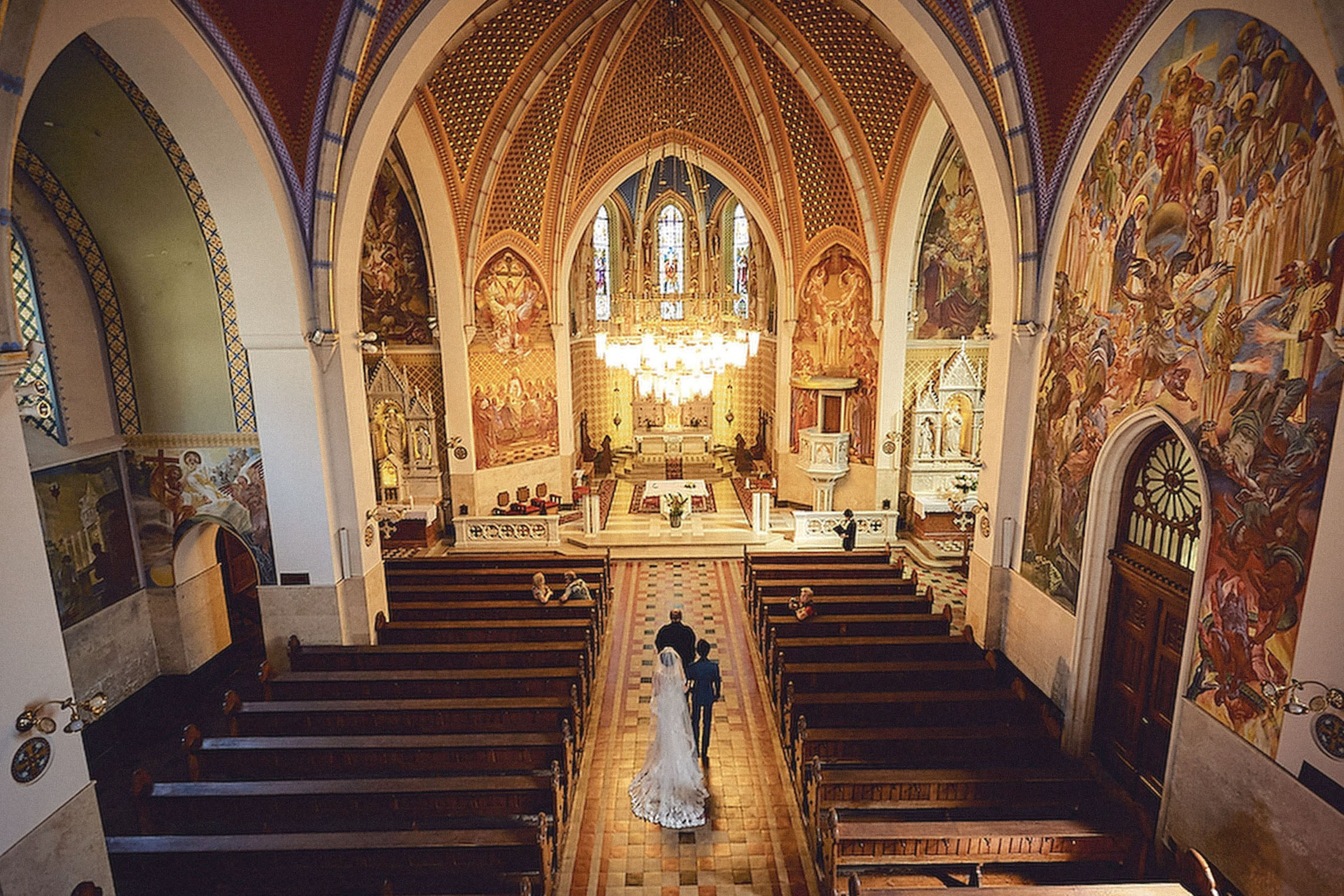Young Japanese bride and groom in stylish attire entering St. Martin's Parish Church, Bled, Slovenia for their wedding ceremony.