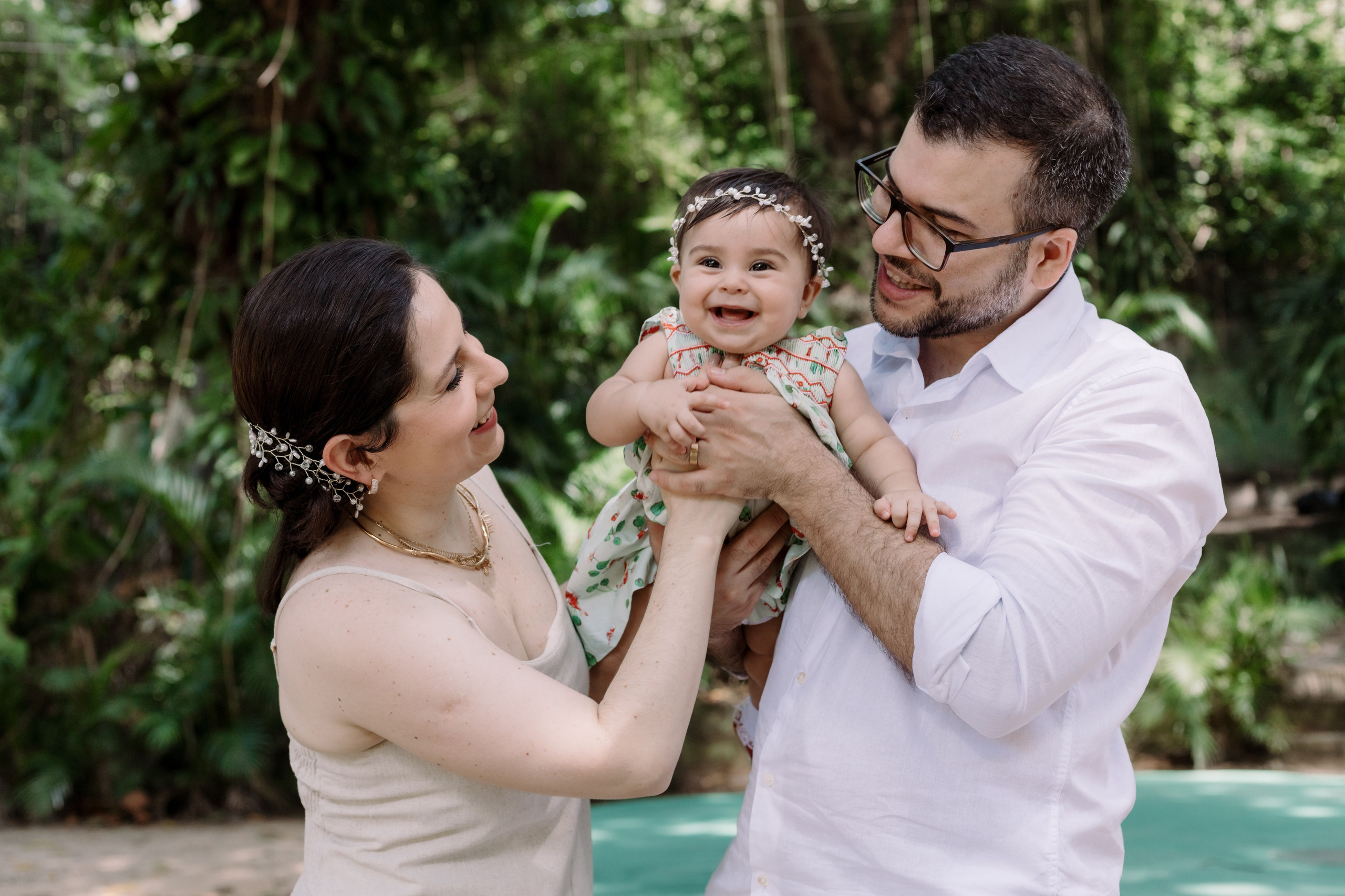 Bebê no colo dos pais em ambiente externo