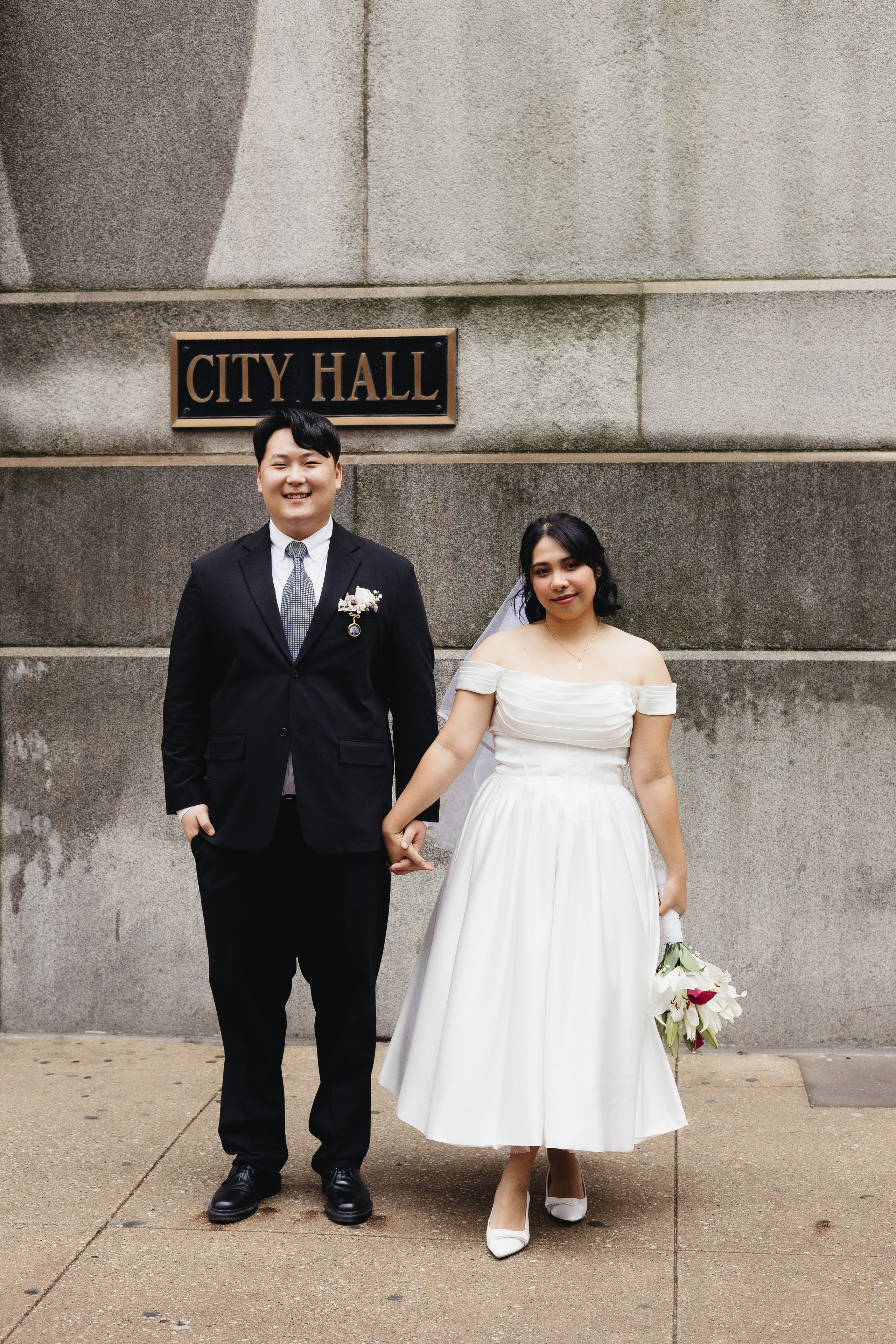 Couple holding hands in front of the City Hall sign in Chicago