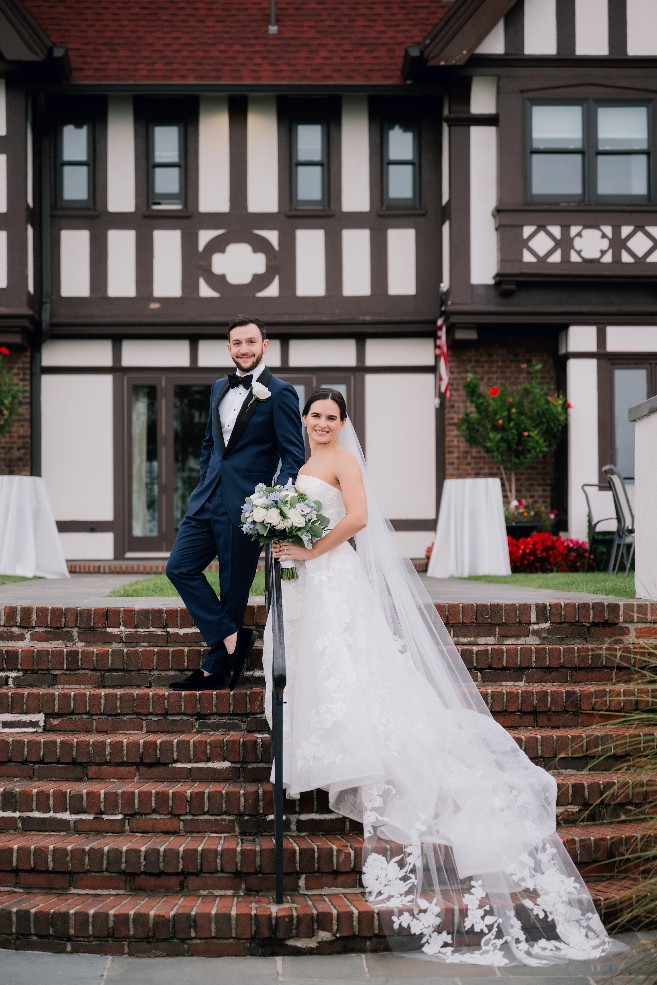 a bride and groom pose on the steps outside of their home