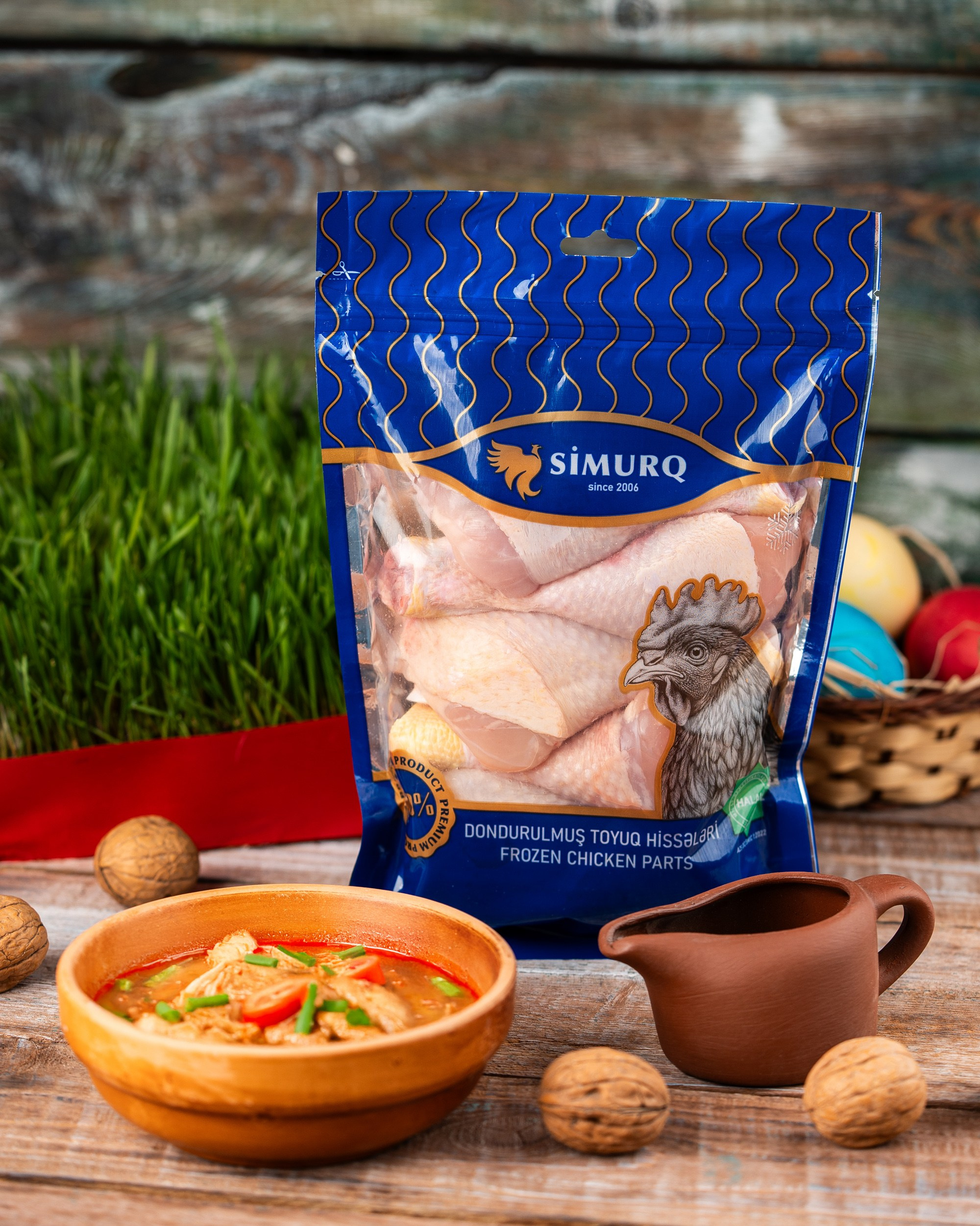Simurq qablaşdırılmış toyuq qanadları və taxta qabda qozlu isti şorba – kənd üslubunda Novruz dekorasiyası ilə məhsul çəkilişi