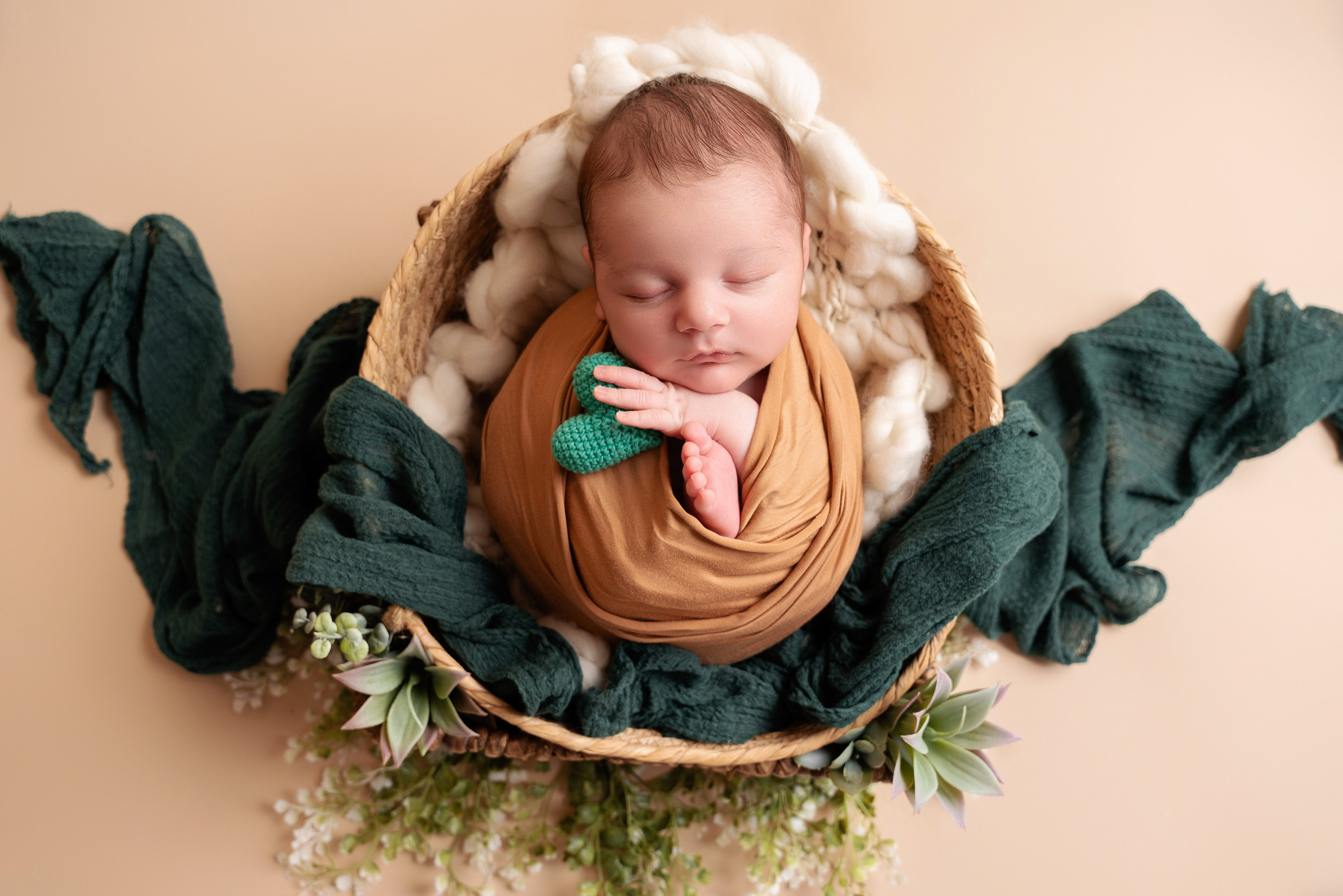 Säugling mit einem grünen gestrickten Herz in der Hand