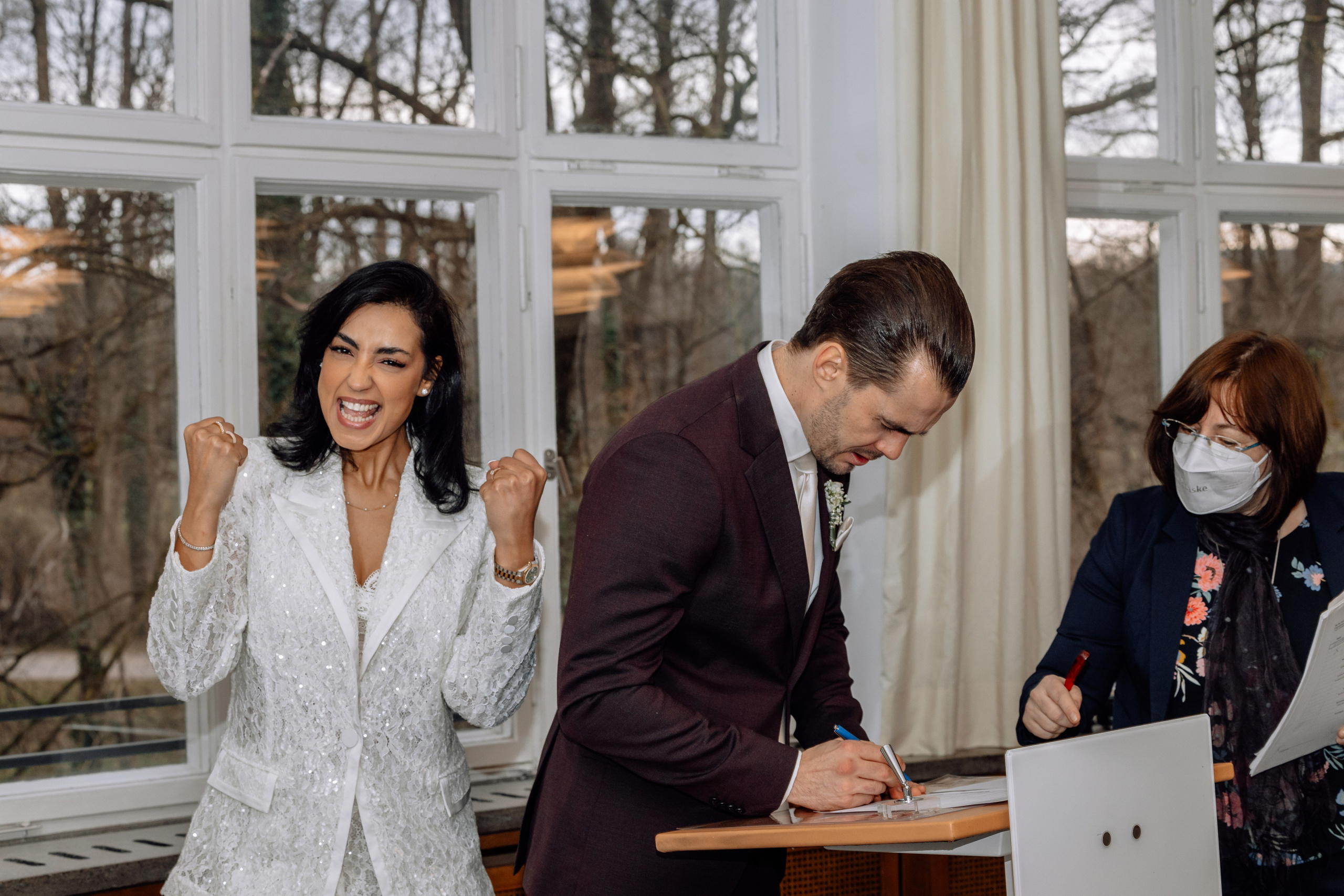 Braut unterschreibt fröhlich Dokumente – glückliche Trauung im Standesamt Schwabing