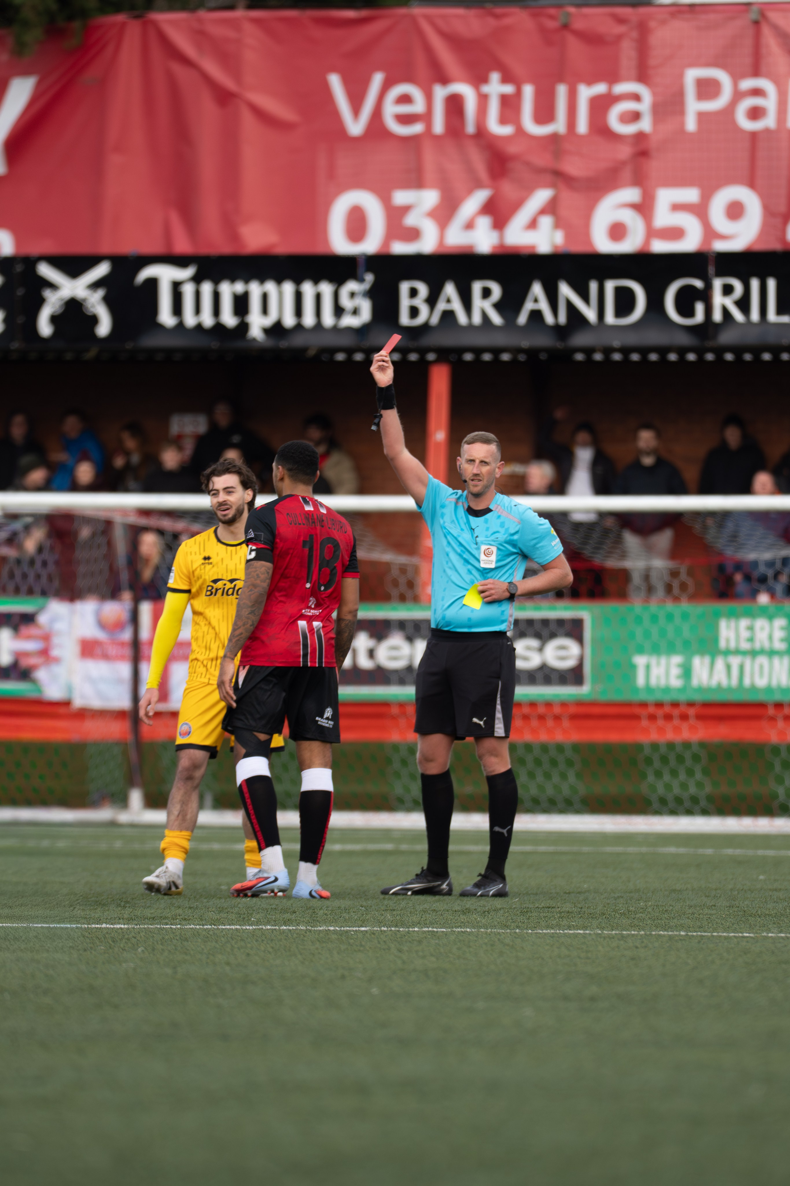 Tamworth, England — February 14, 2026: Referee Jamie O’Connor shows a red card to Aldershot Town’s Keane Anderson during the Enterprise National League match between Tamworth and Aldershot Town at The Lamb Ground. Photo: Jay Soundo