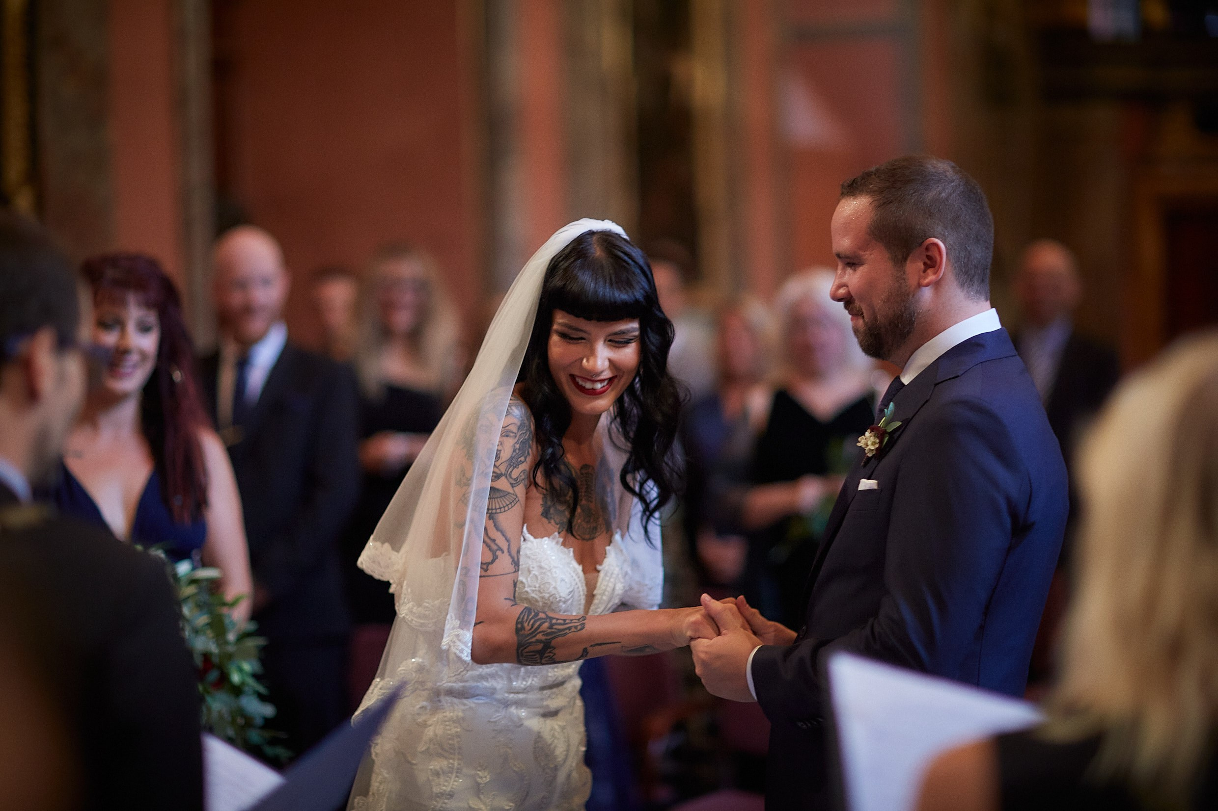 Emotional burlesque bride gripping groom's hands tightly ceremony.
