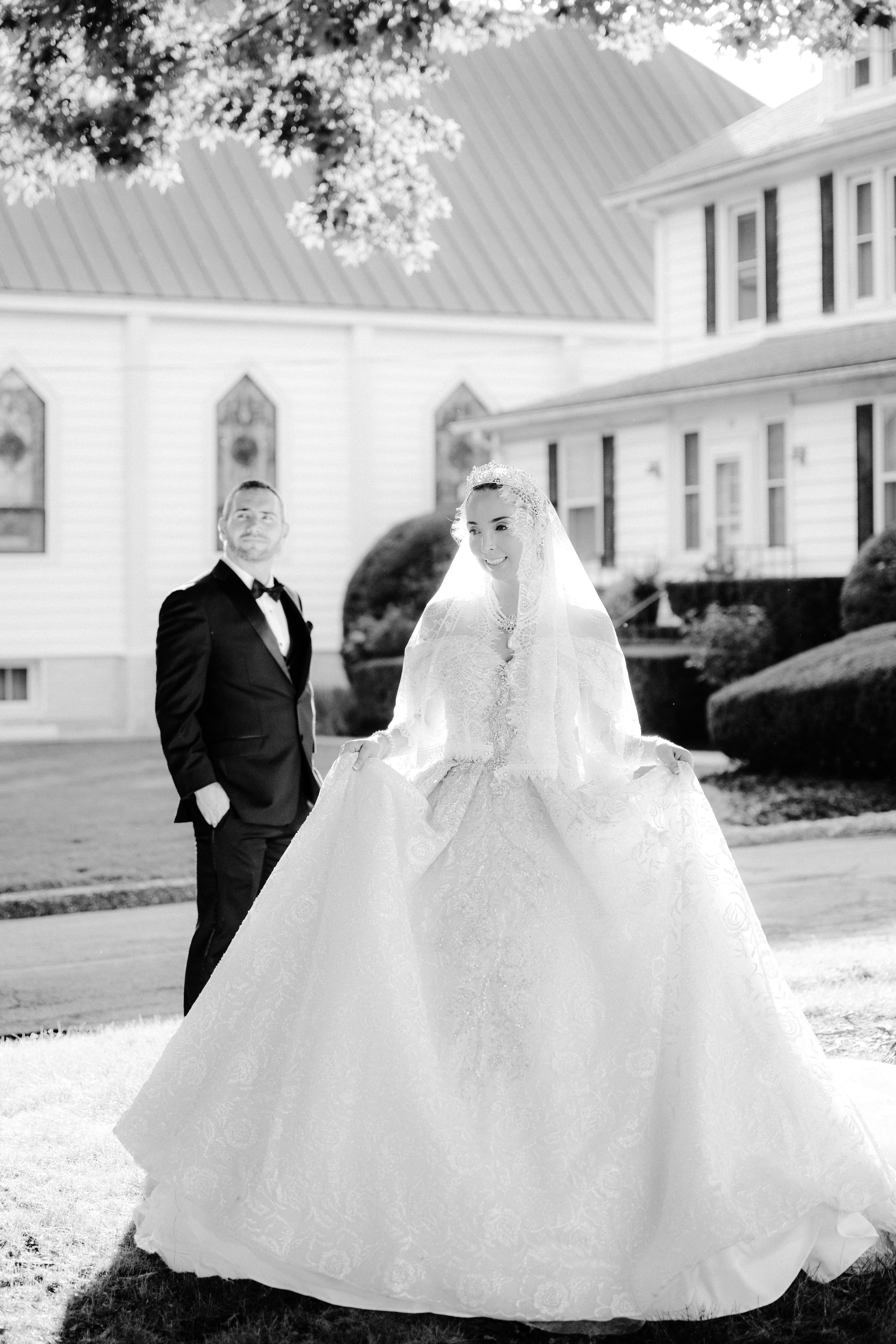 a bride and groom pose for a photo in front of a white house