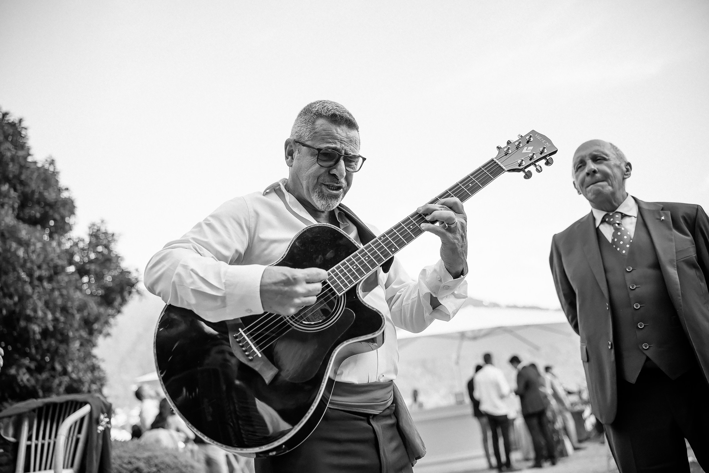 Guitarist entertains guests with lively music, smiling beside a guest.