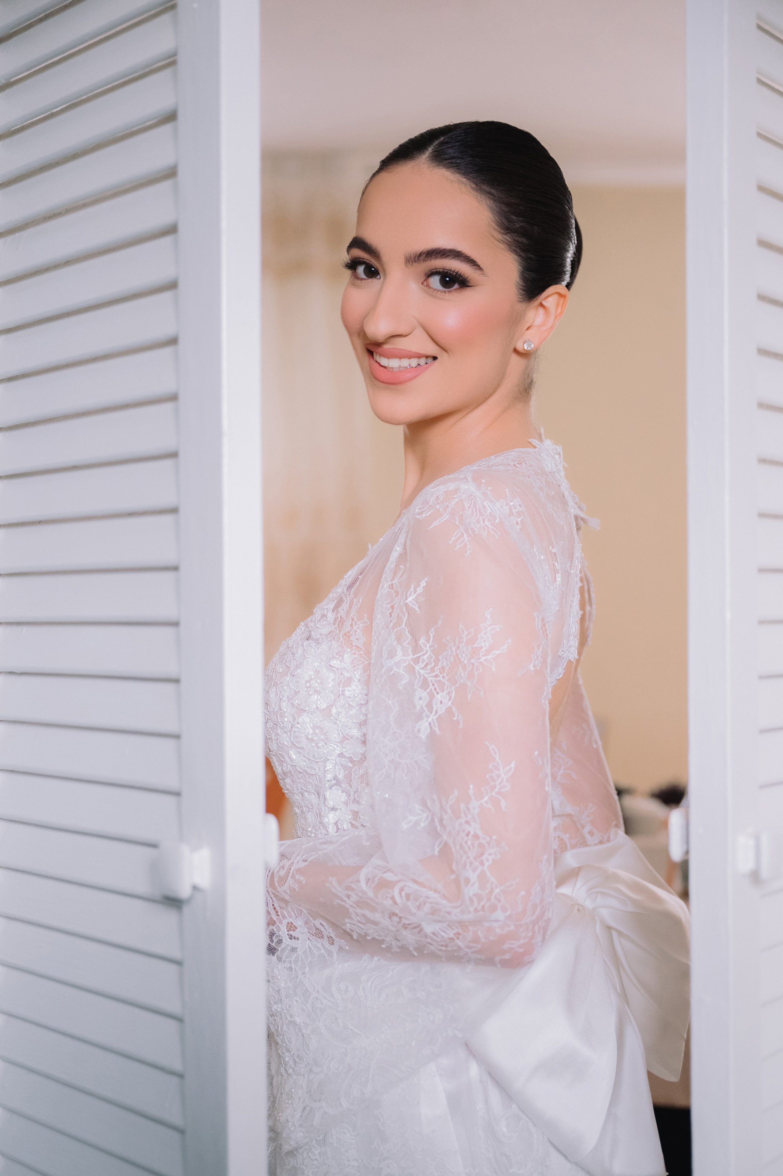 a bride in a white dress standing in front of shutters