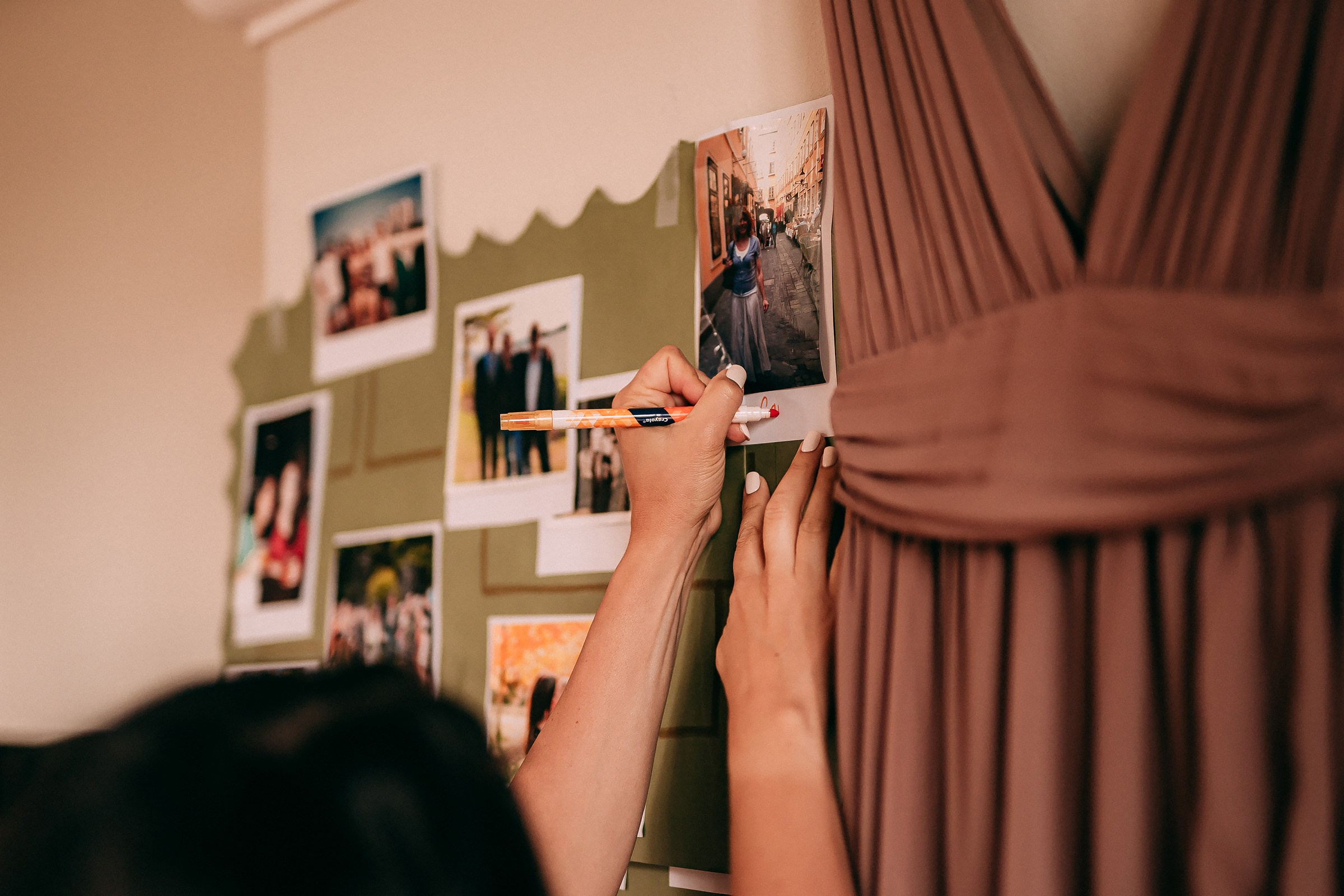 A person attaches a photo to a memory board filled with personal pictures, creating a nostalgic display.