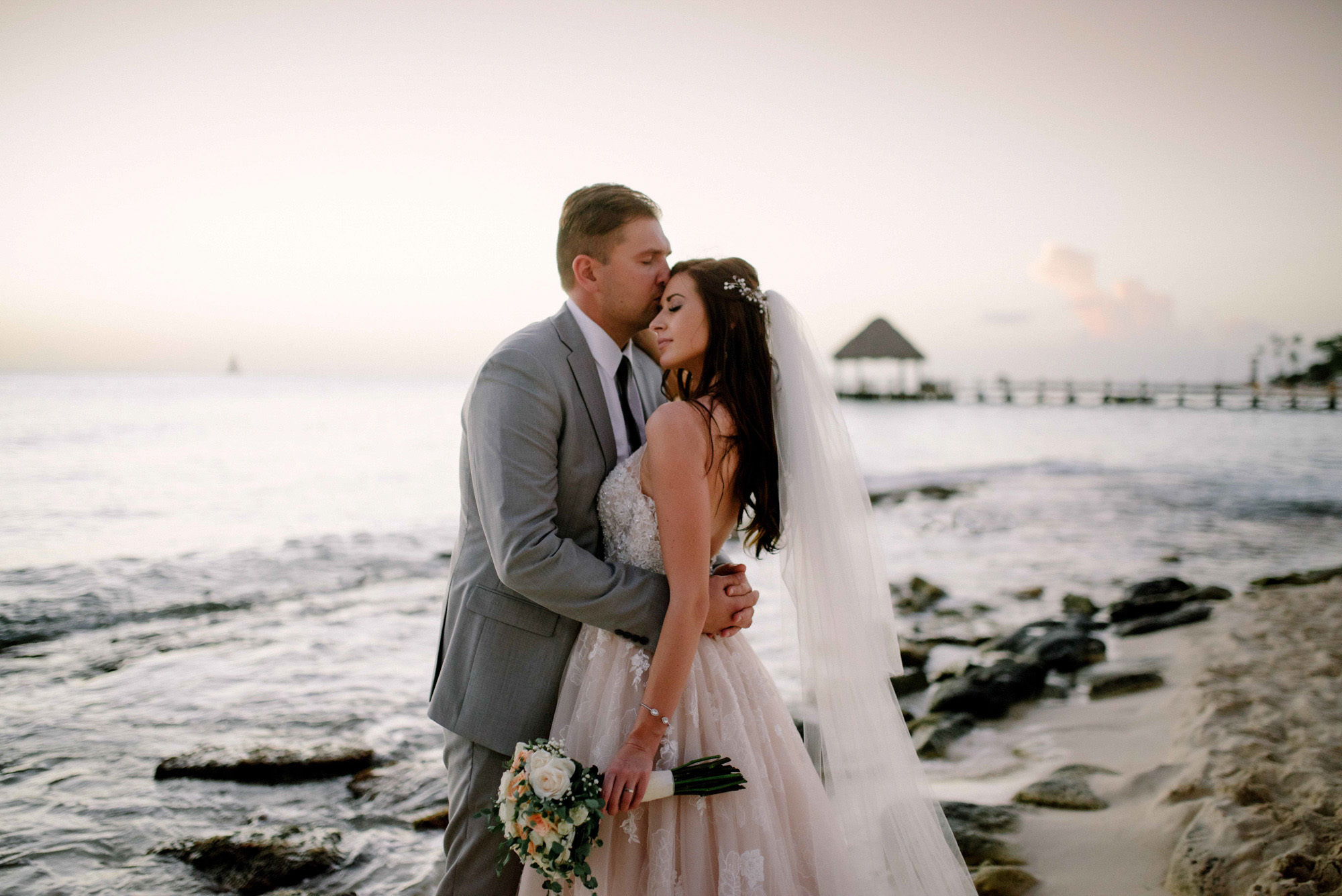 The groom embraces the bride on the background of the sea bay.