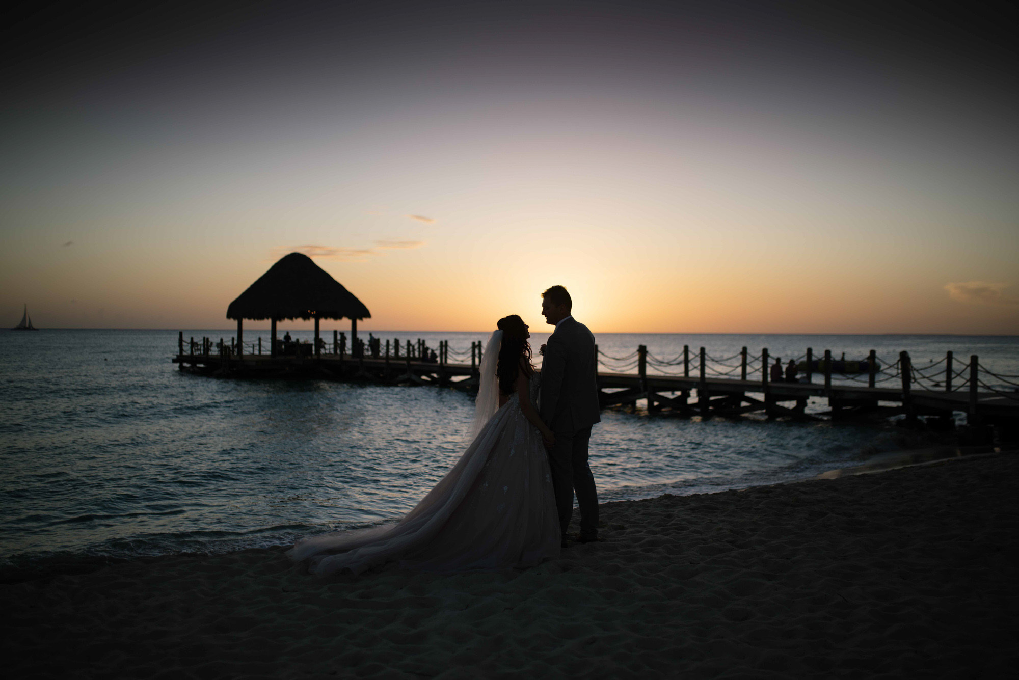 Bride and groom stand embracing at sunset on the background of the sea beach.