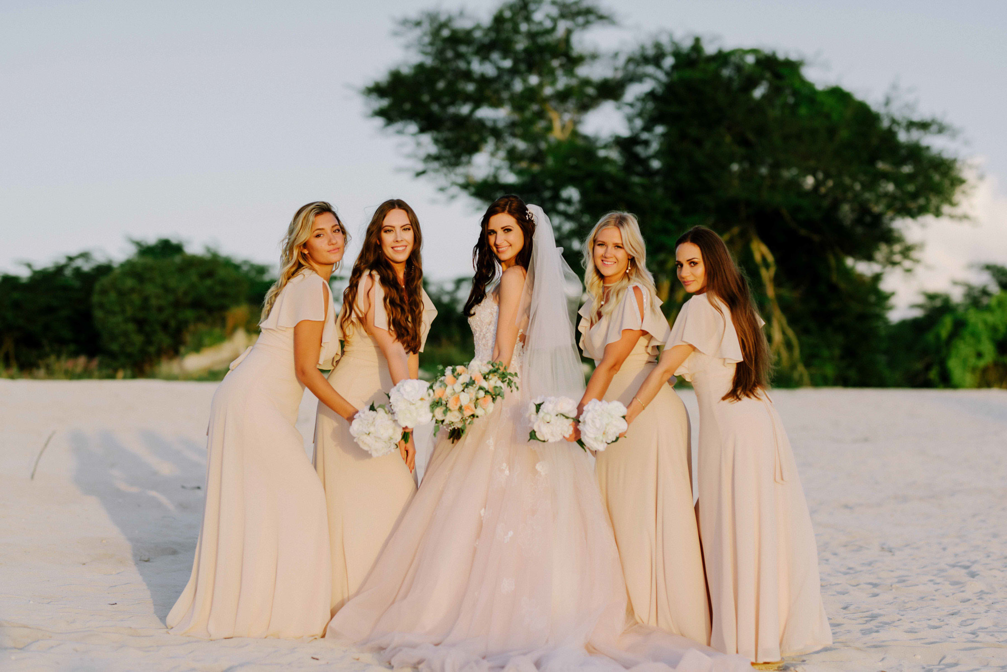 Bride and bridesmaids on the background of the beach and green trees.