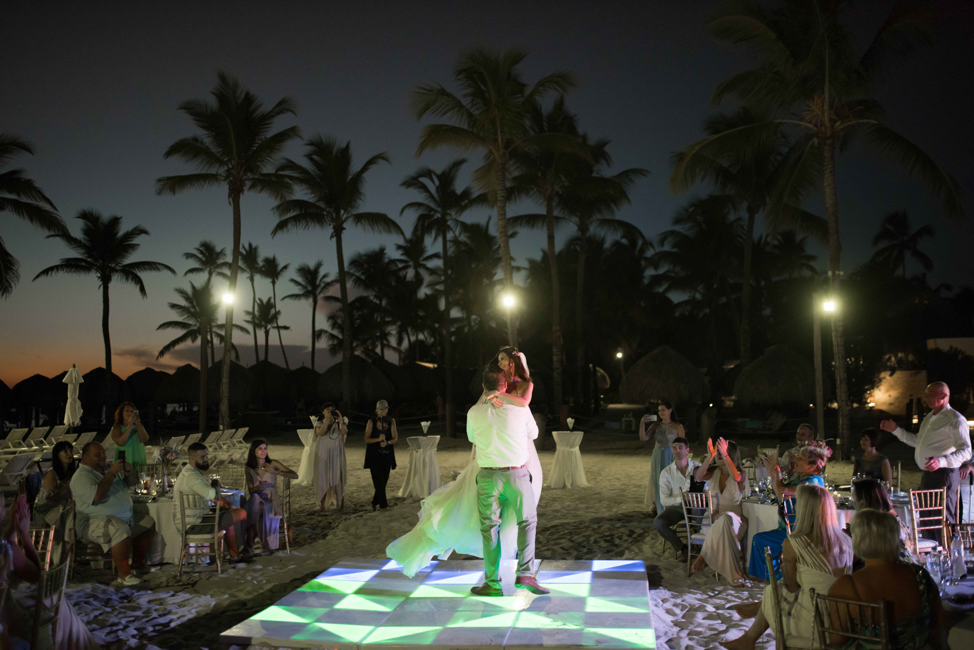 Bride and groom on the dance floor in the background of night, night lighting surrounded by guests.