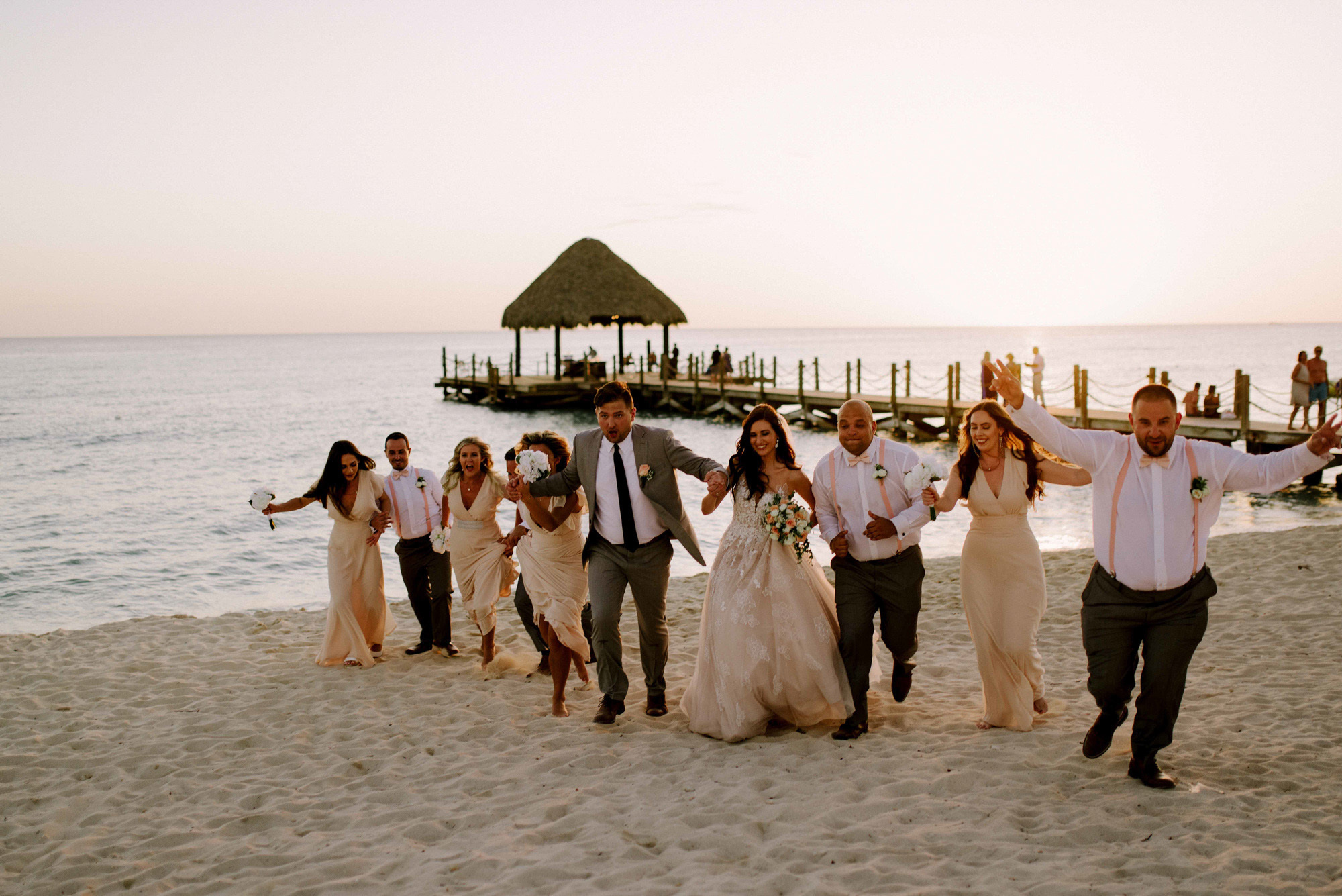 The bride and groom together with friends are walking along the sea beach.