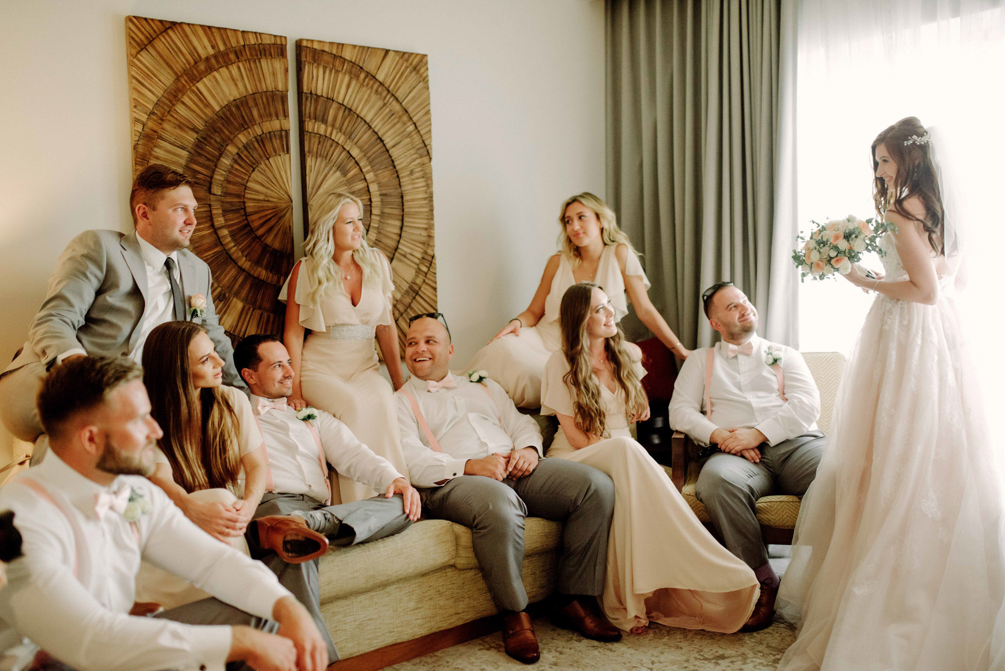 The bride came into the room with her friends with a bouquet of flowers.