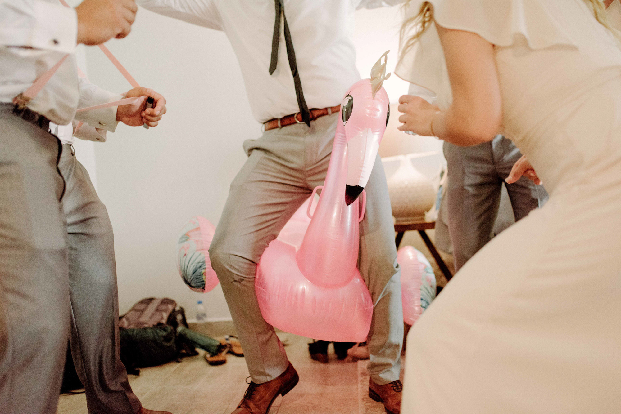 The groom rides an inflatable flamingo.