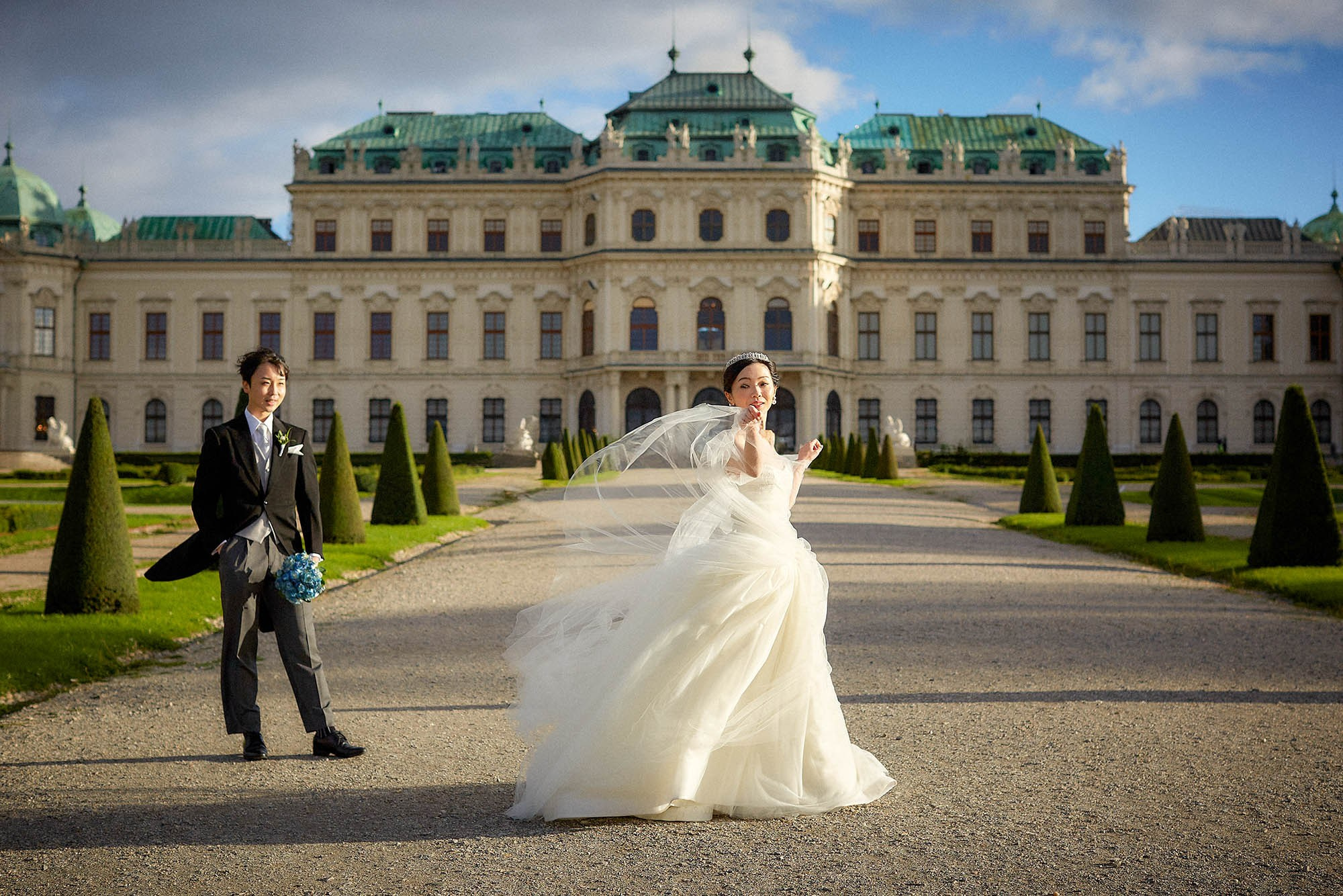 Bride flipping wedding dress in wind smiling at Belvedere Palace.