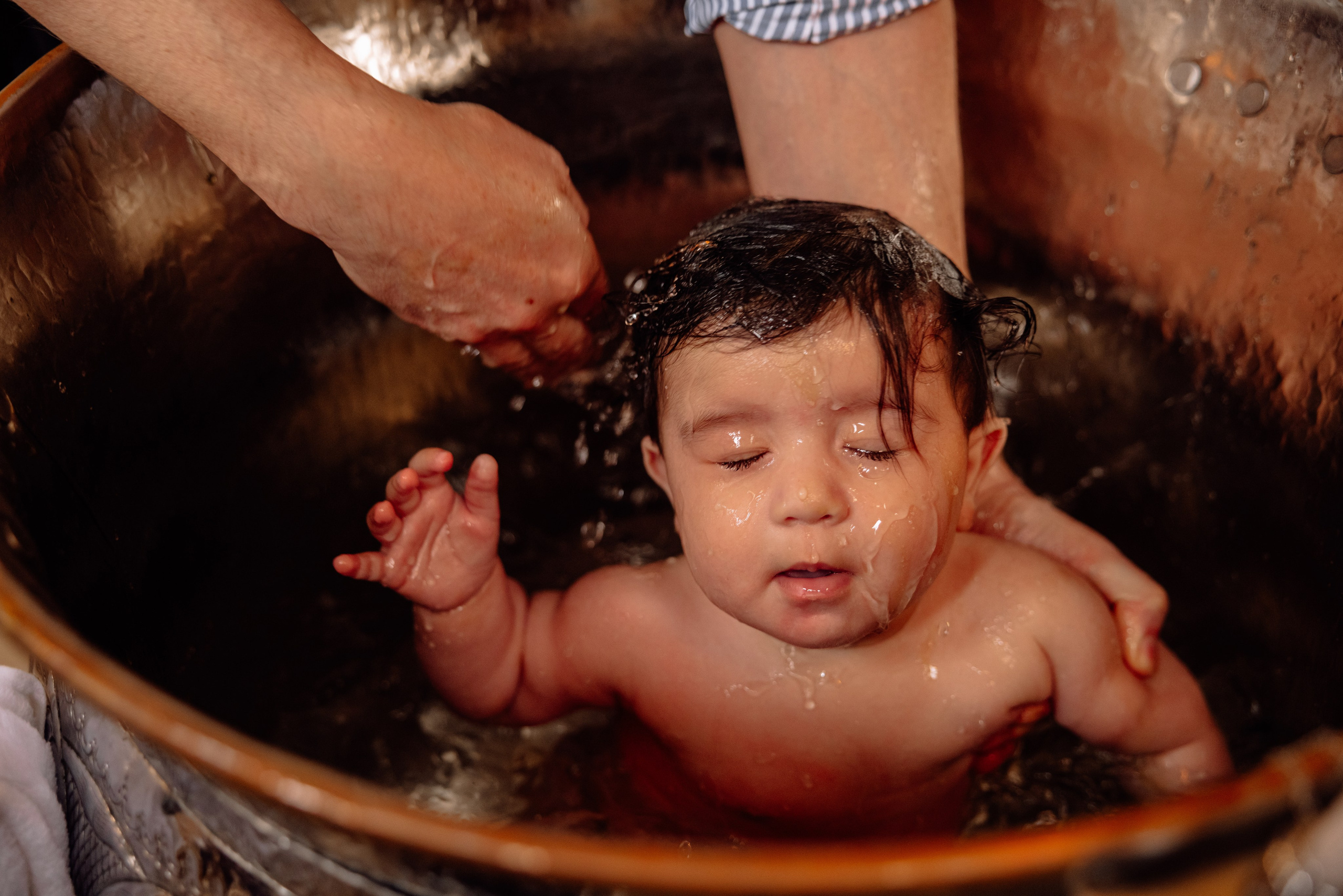 Tauffotografie München – glücklicher Moment während der Taufe im Wasser