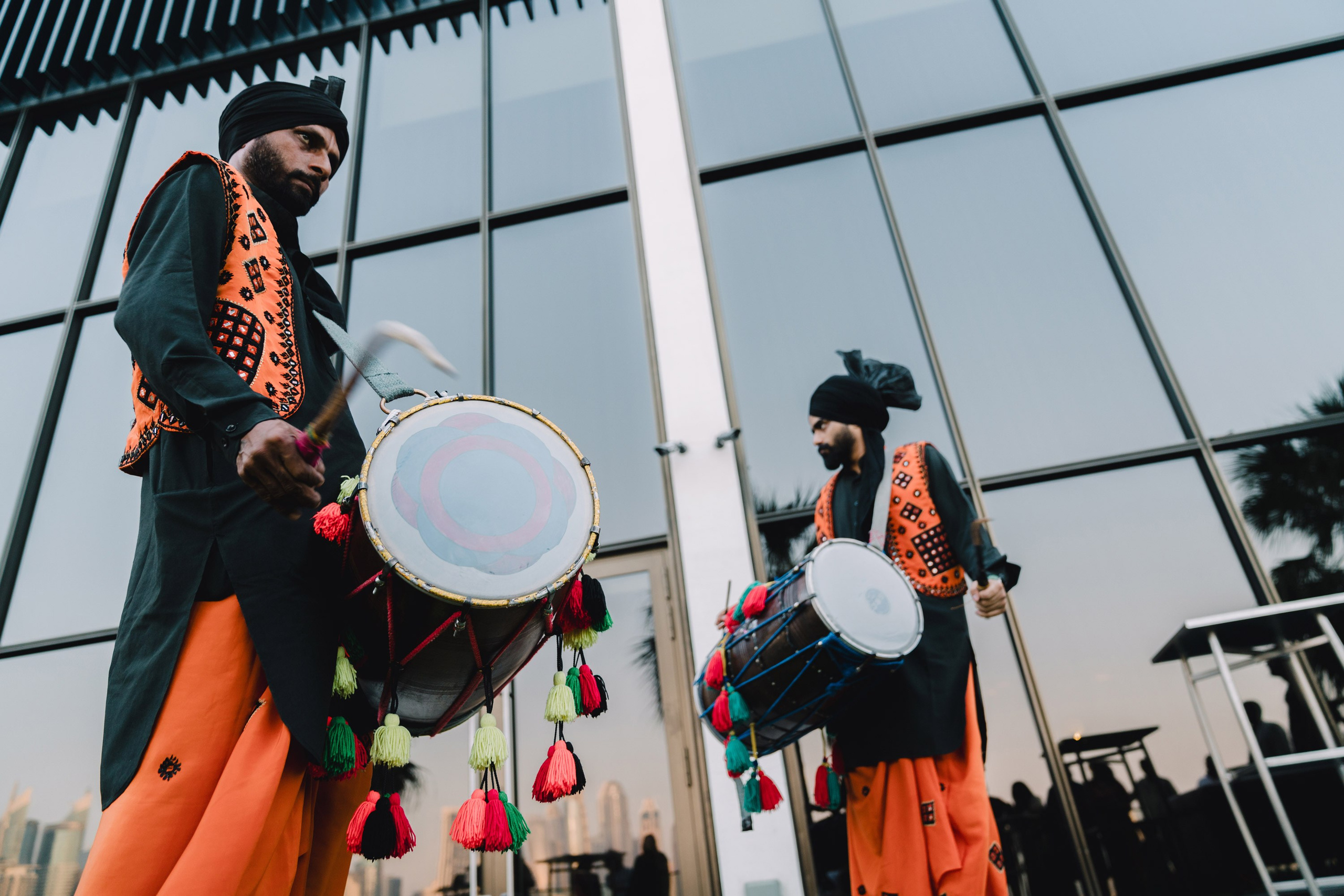 Two indian drummers dressed in national suites are playing on drums