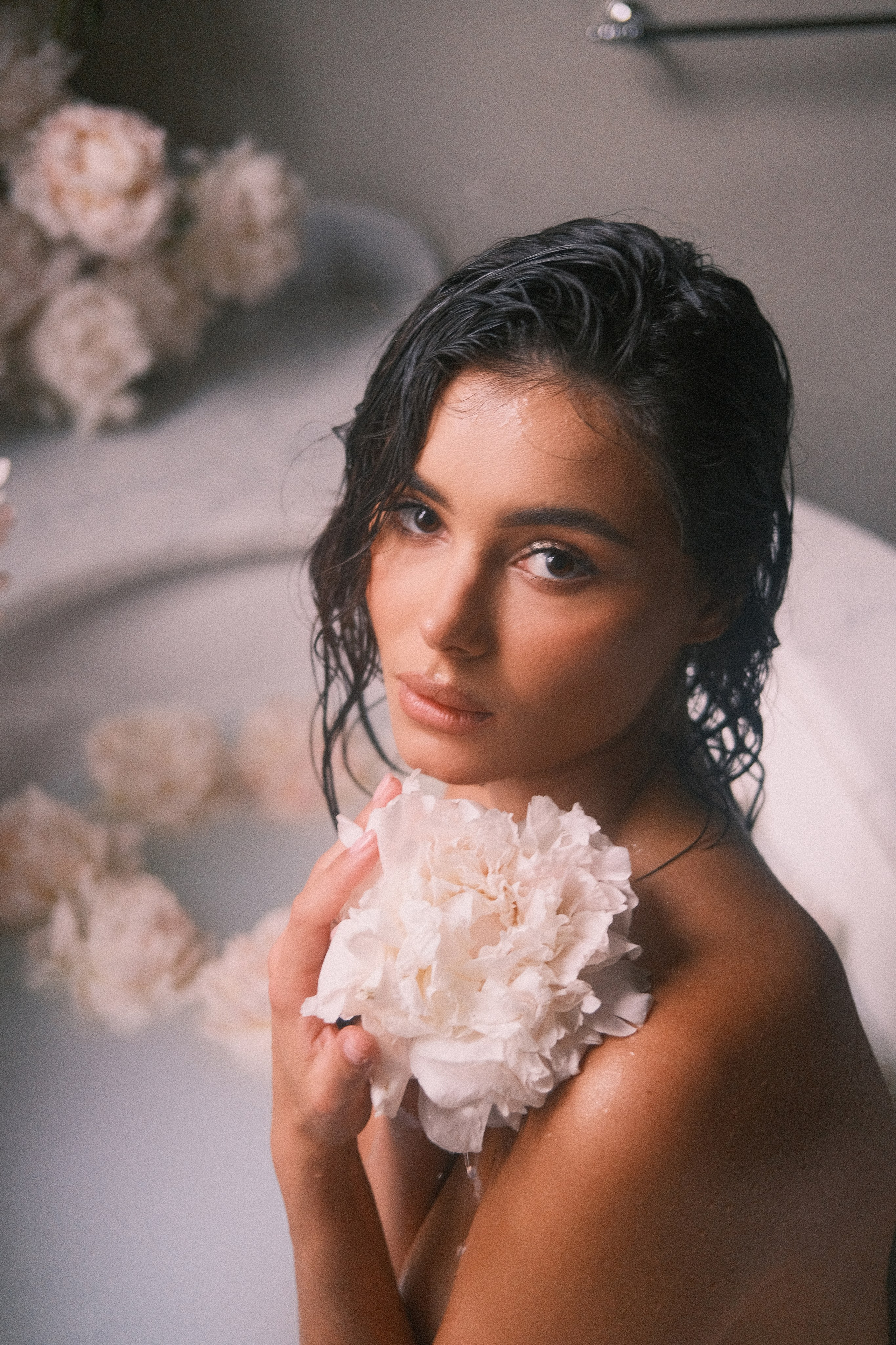 A soft-focus shot of a woman holding a delicate flower close to her face, emphasizing a sense of connection with nature and beauty.