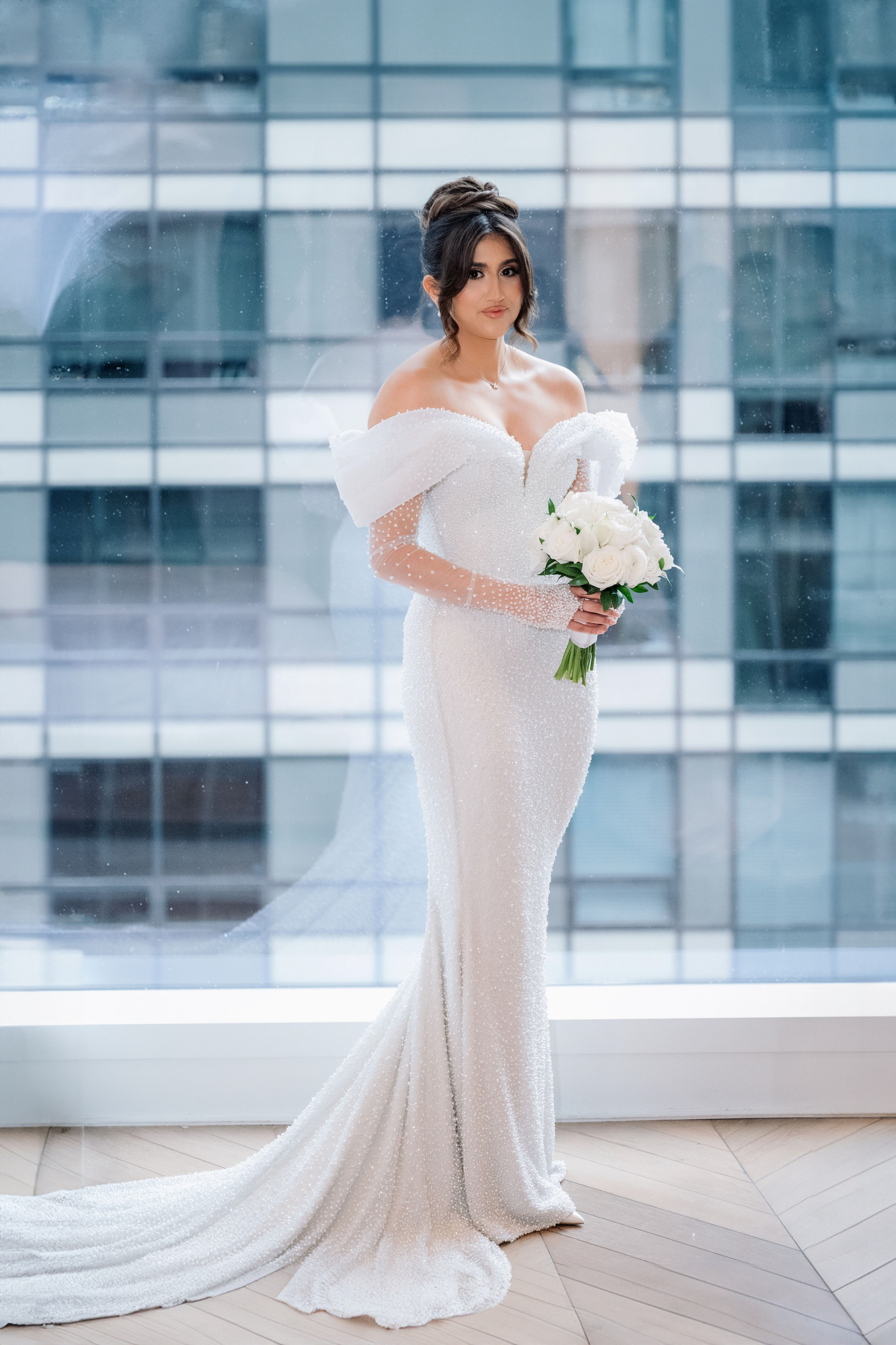 a bride in a white gown standing in front of a window